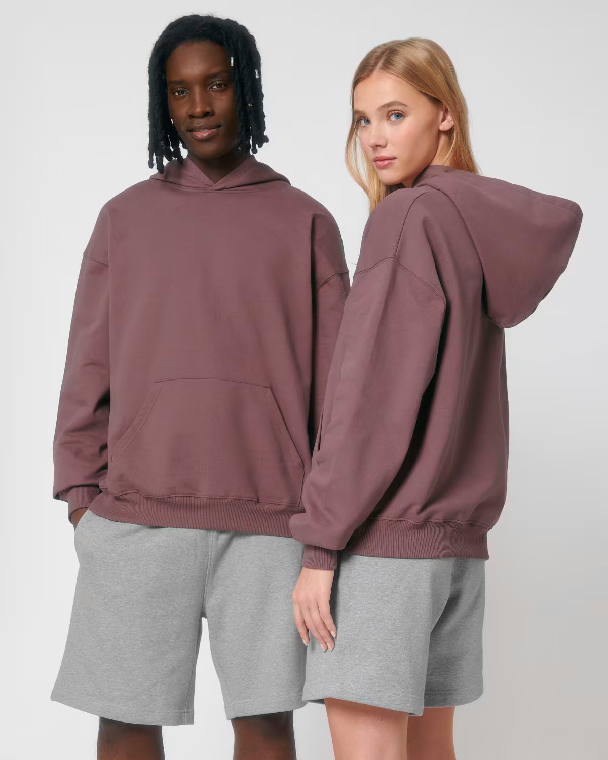 Front view of a male and female model wearing dusty rose cotton hoodies in studio