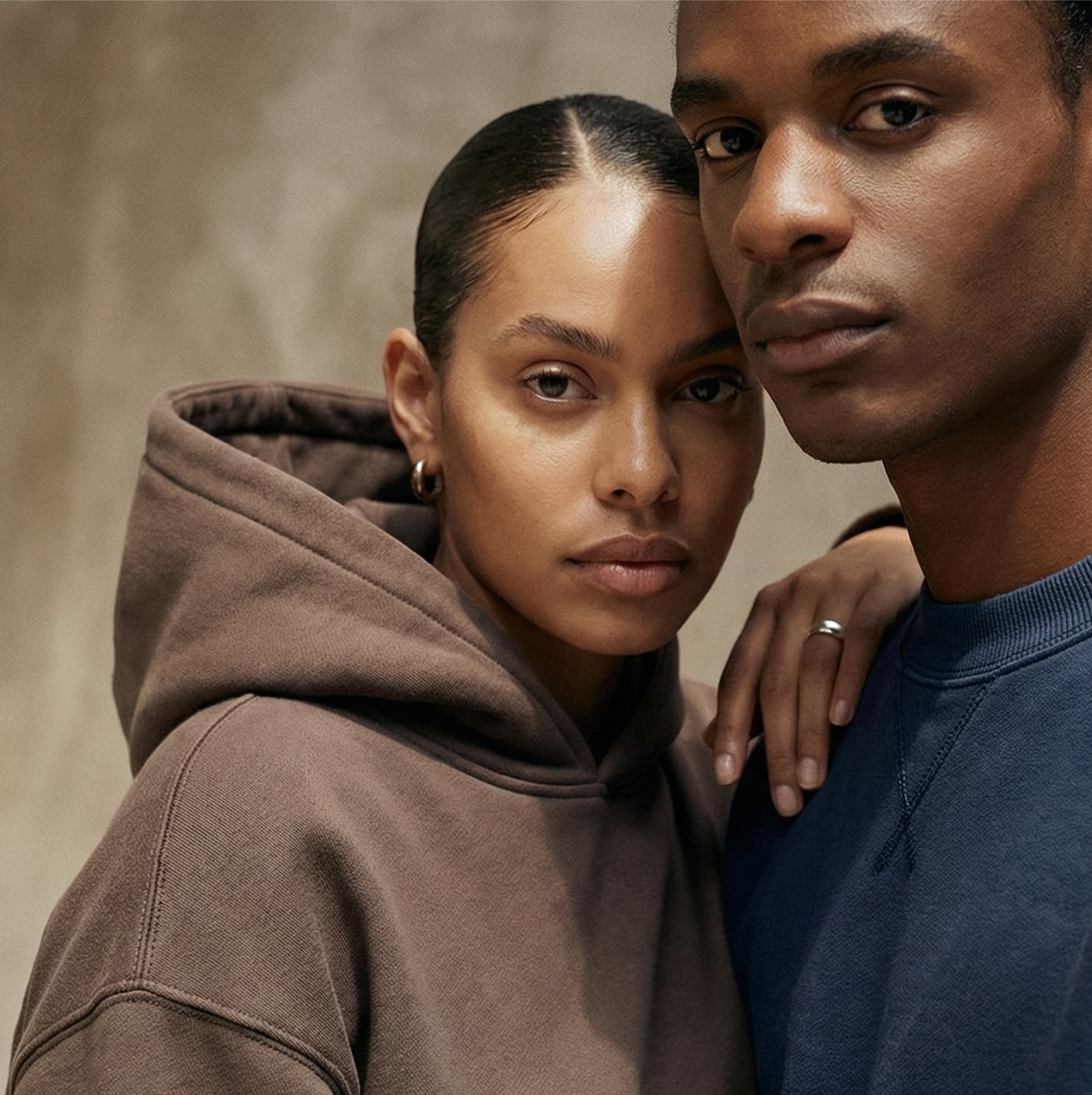 Two people standing close together against a neutral background