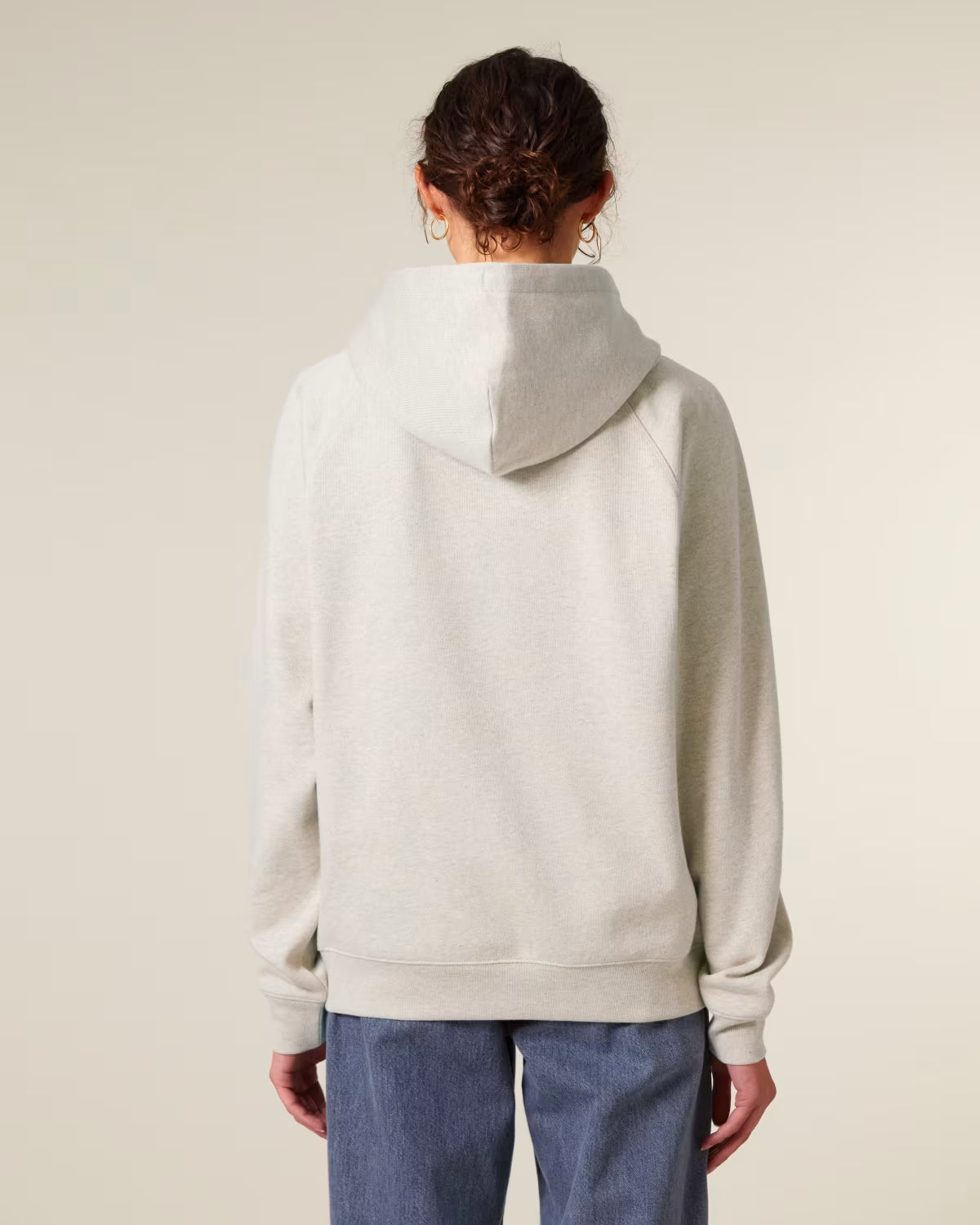 Back view of a male model wearing a beige cotton hoodie in studio