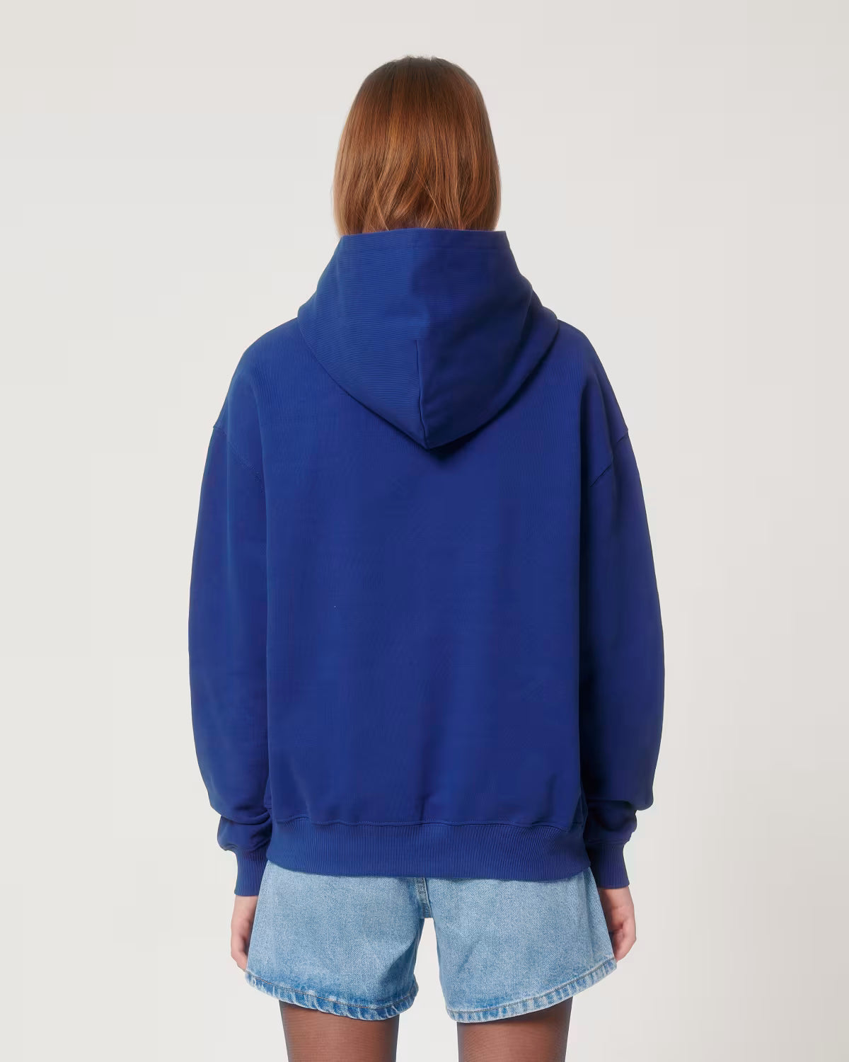 Back view of a male model wearing a royal blue cotton hoodie in studio