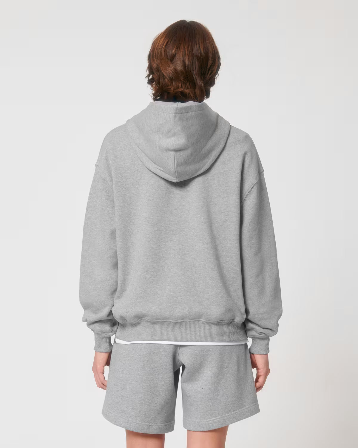 Back view of a male model wearing a light grey cotton hoodie in studio