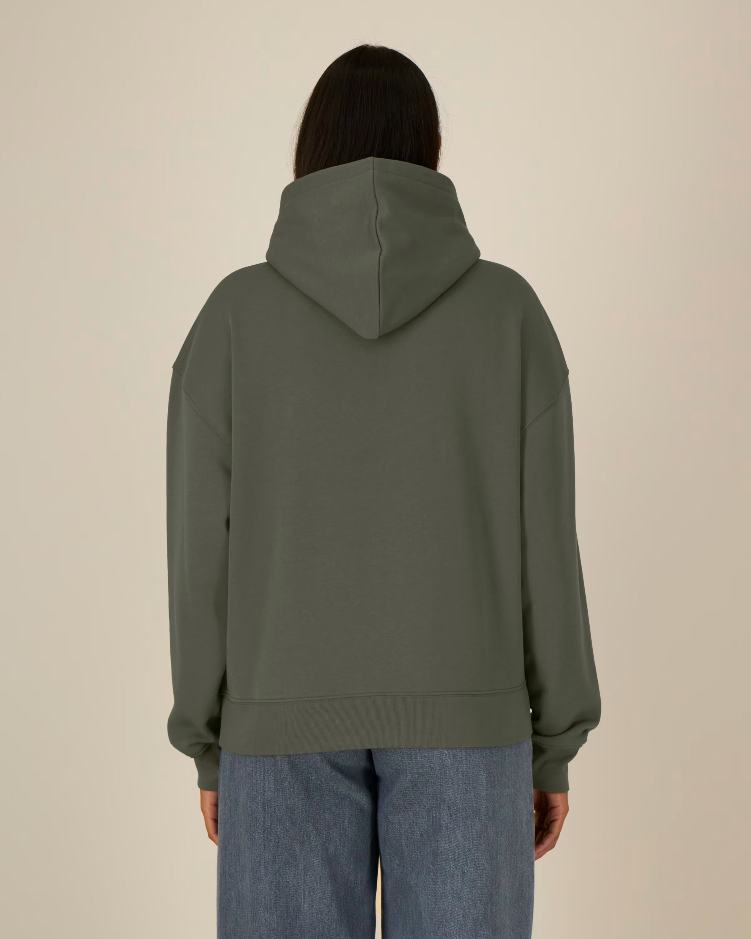 Person wearing a green unisex cotton hoodie from behind on a beige background