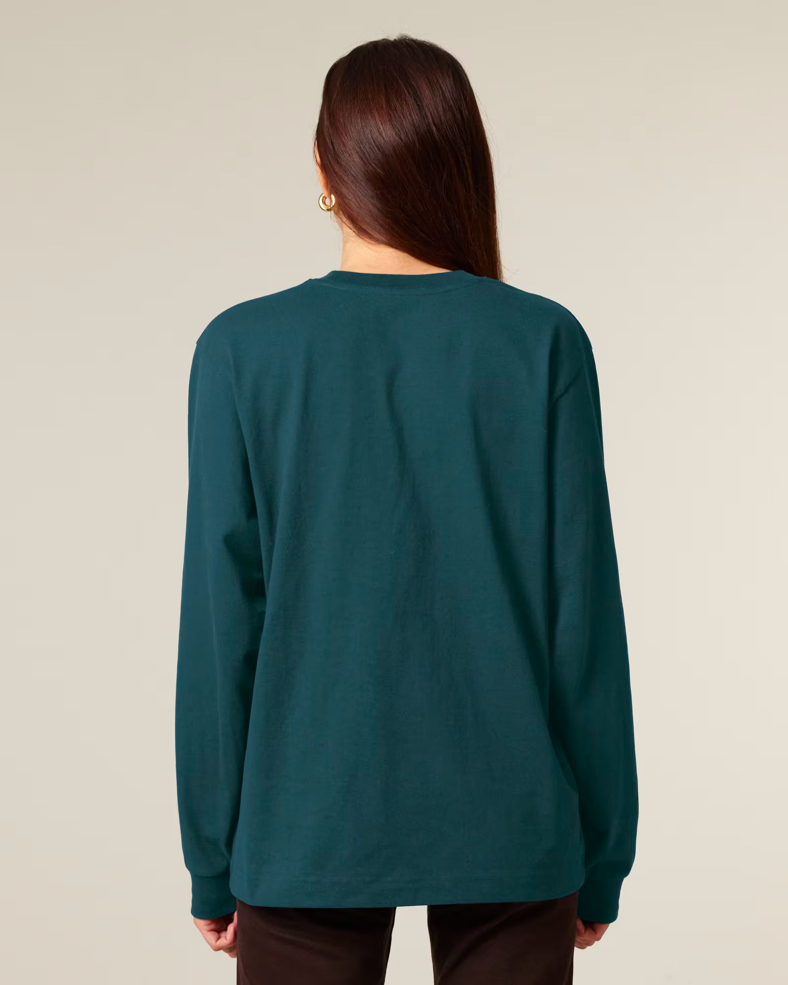 Back view of a female model wearing a teal green cotton long sleeve t-shirt in studio