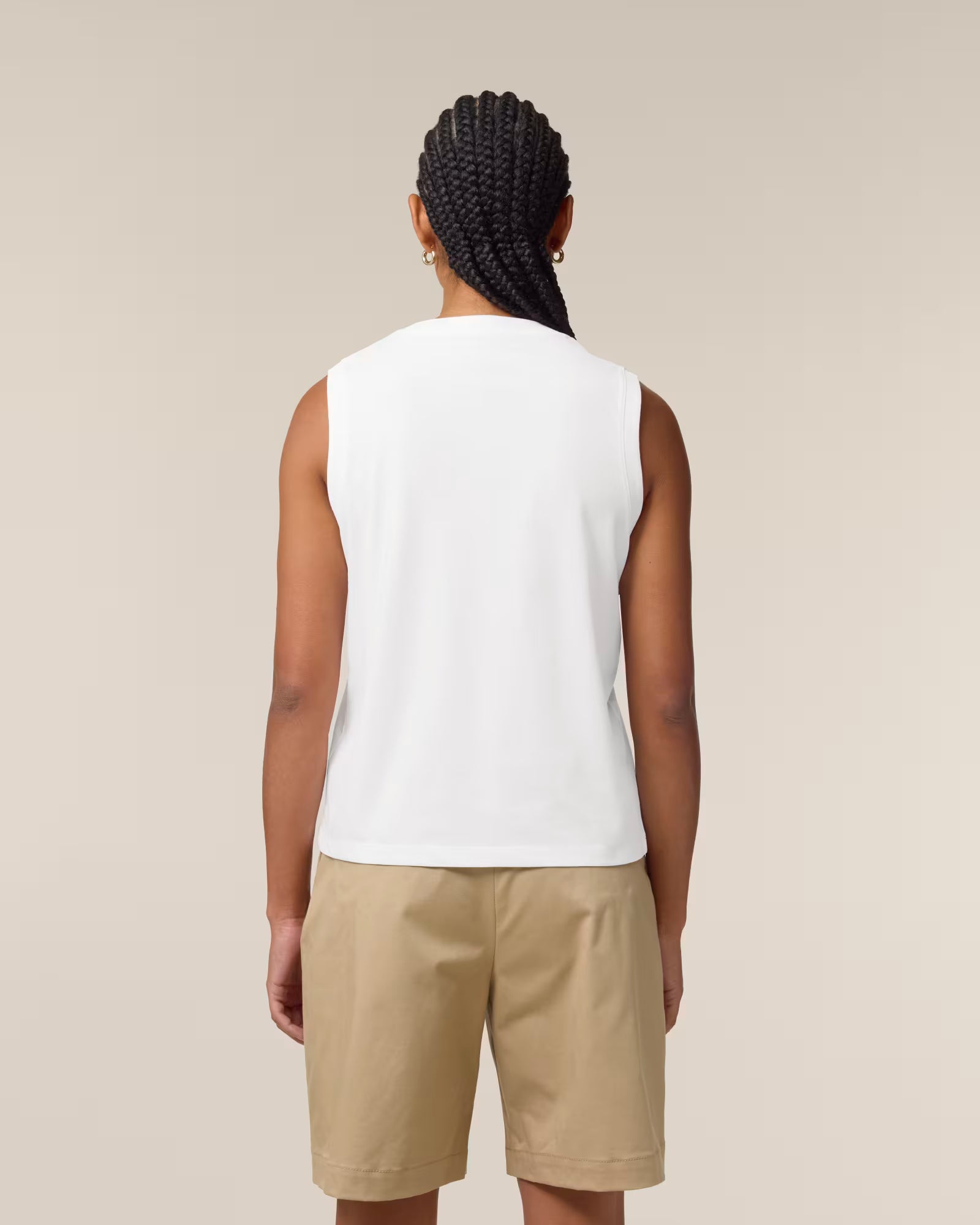 Back view of a female model wearing a white cotton sleeveless top in studio