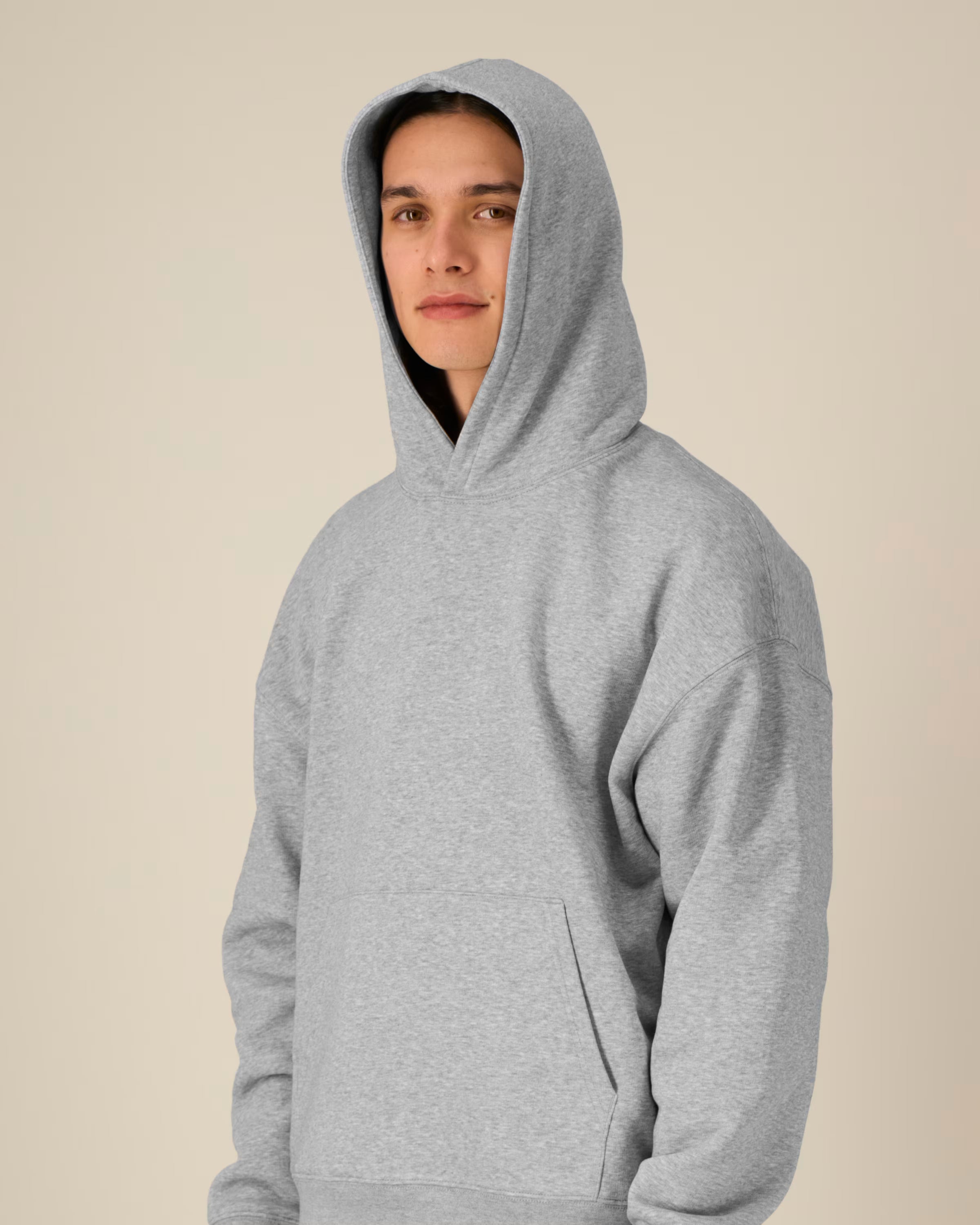 Person wearing a gray unisex cotton hoodie against a beige background