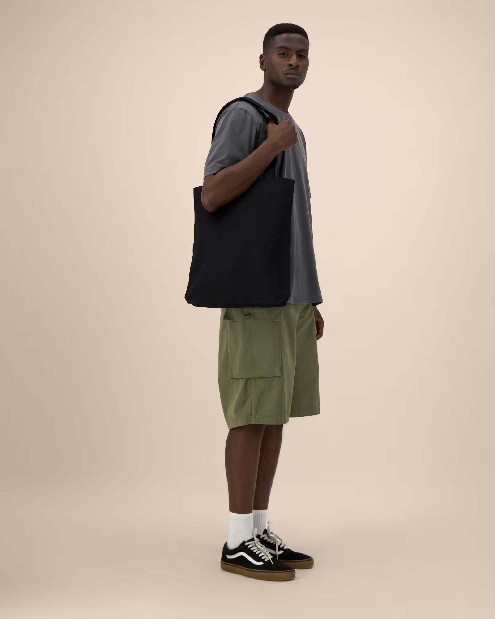 Black canvas tote bag worn over shoulder by model