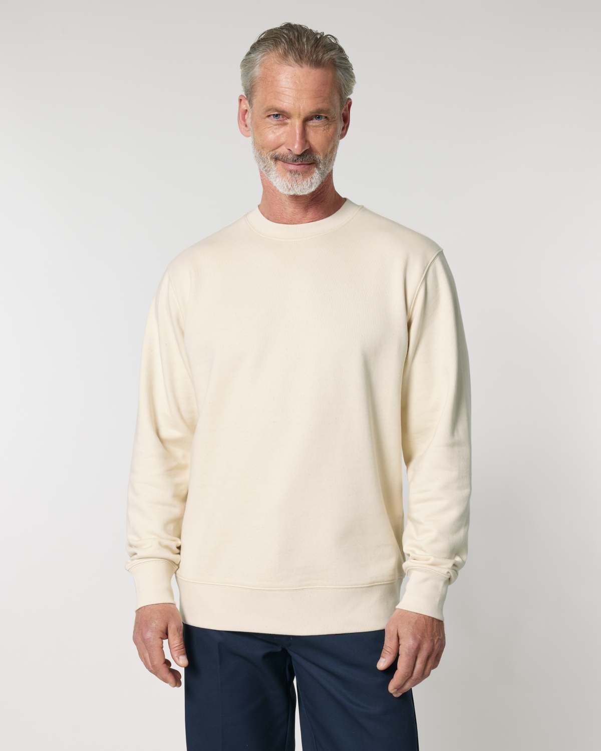 Man wearing a cream unisex cotton sweater against a plain background