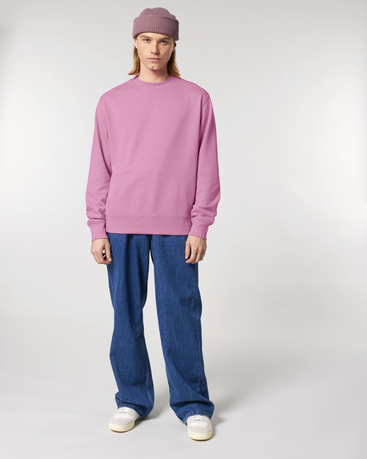 Person wearing a unisex cotton pink sweatshirt and blue jeans on a white background