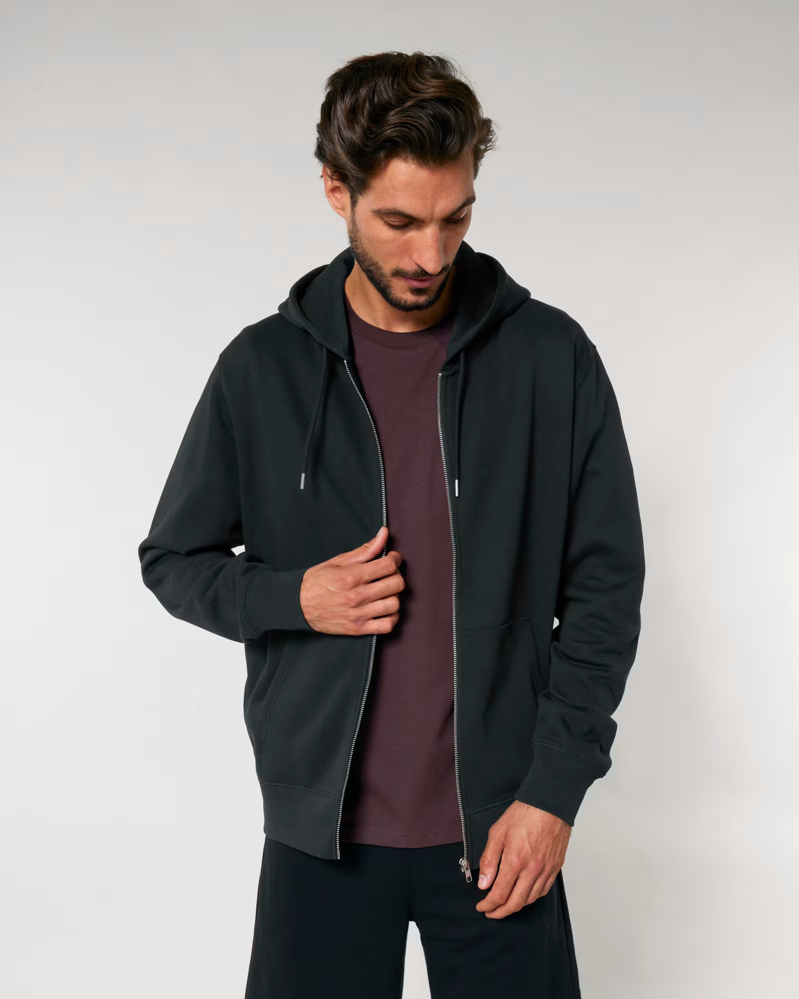 Man wearing a unisex cotton black hoodie on a plain background
