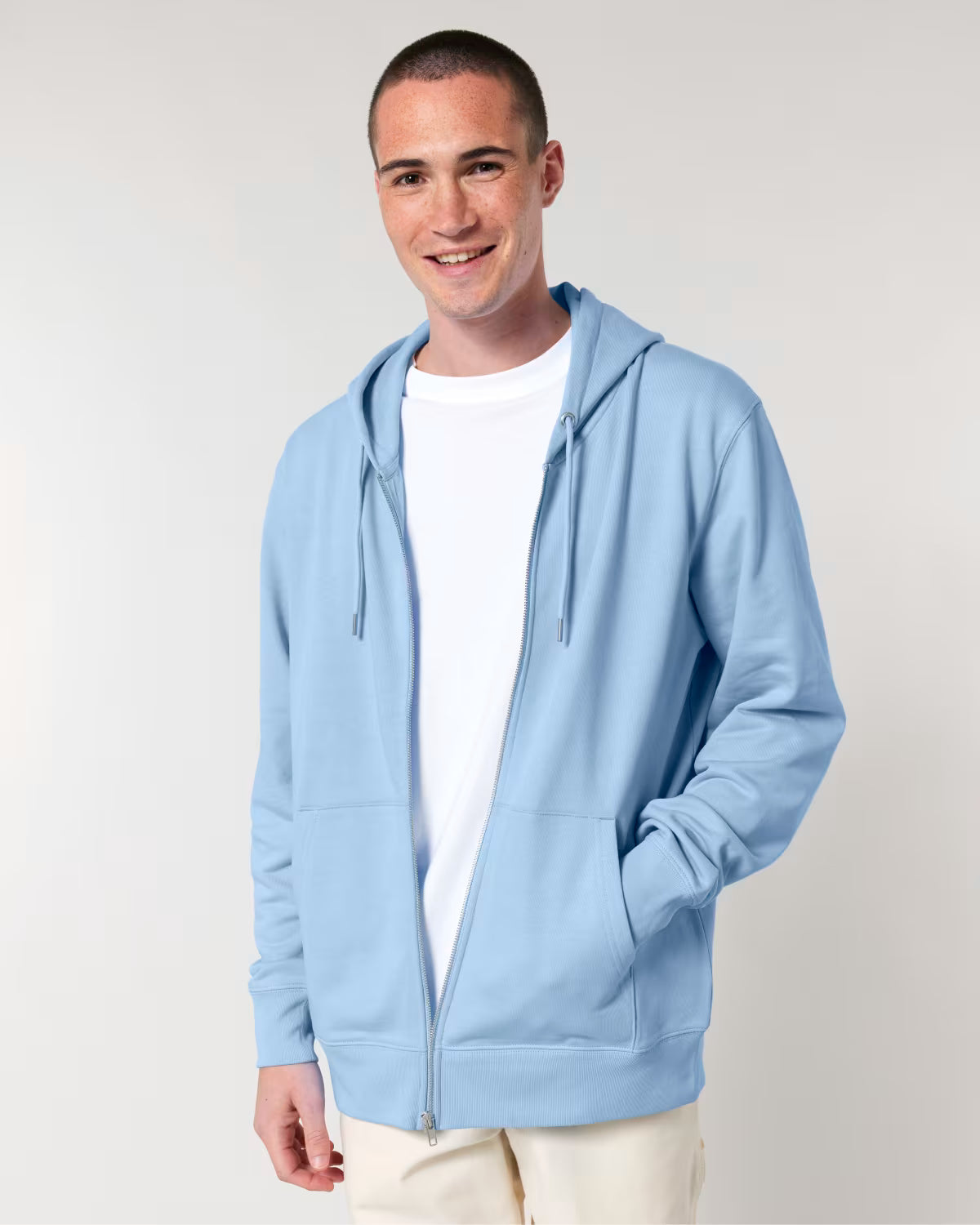 Man wearing a light blue hoodie over a white shirt on a plain background