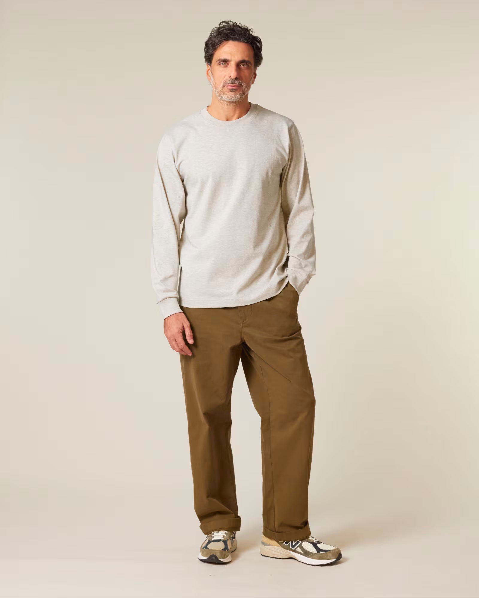 Full body front view of a male model wearing a light beige cotton long sleeve t-shirt in studio