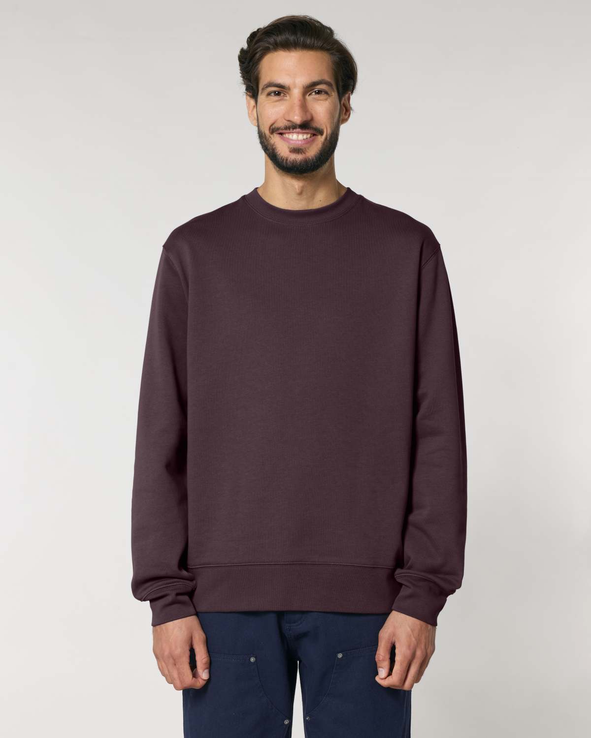 Man wearing a unisex cotton sweatshirt against a plain background