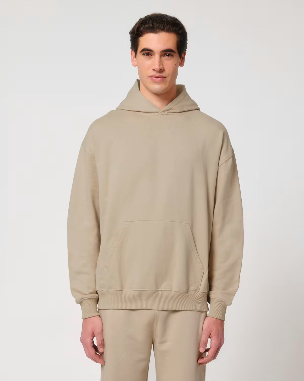 Front view of a male model wearing a beige cotton hoodie in studio