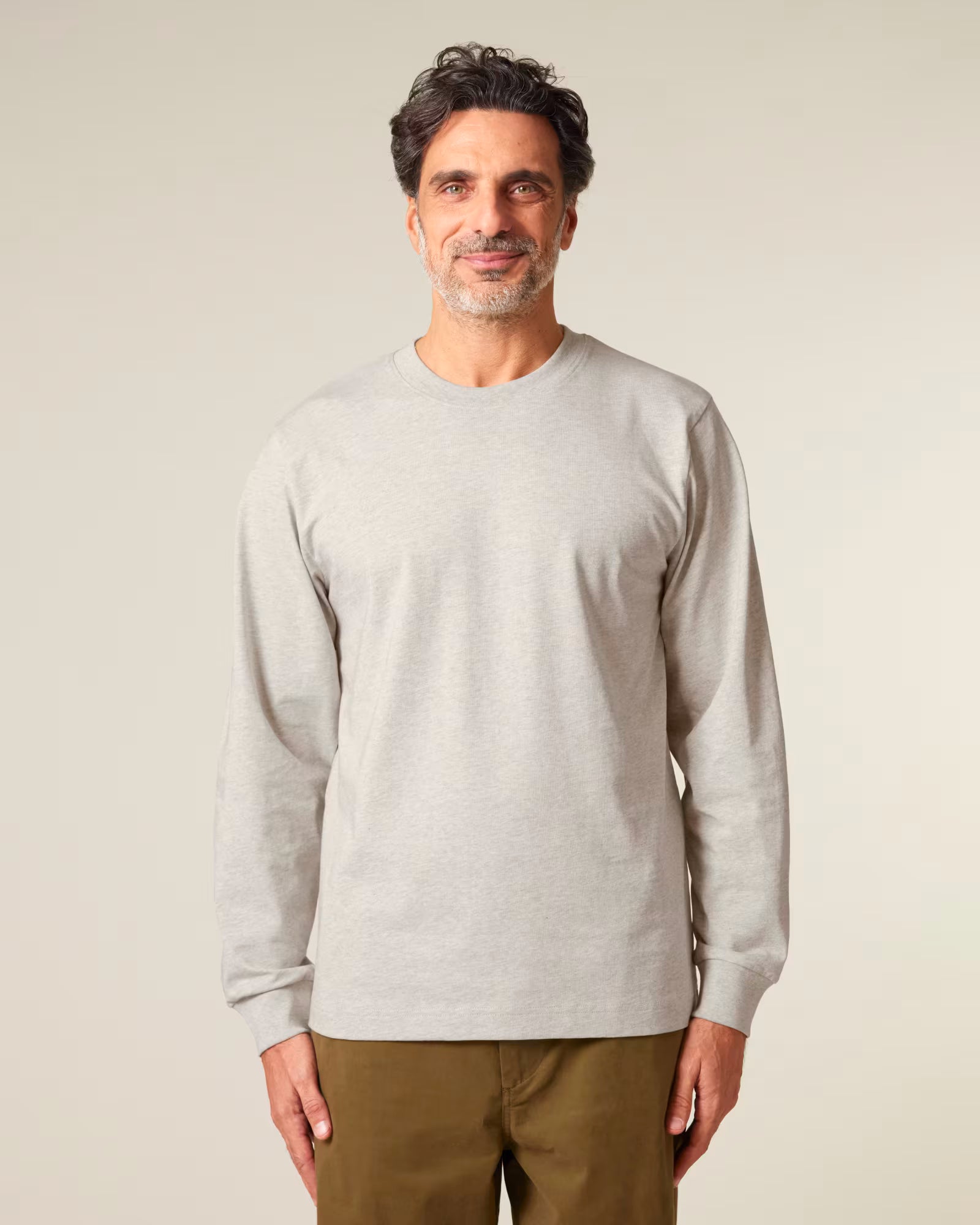 Front view of a male model wearing a light beige cotton long sleeve t-shirt in studio