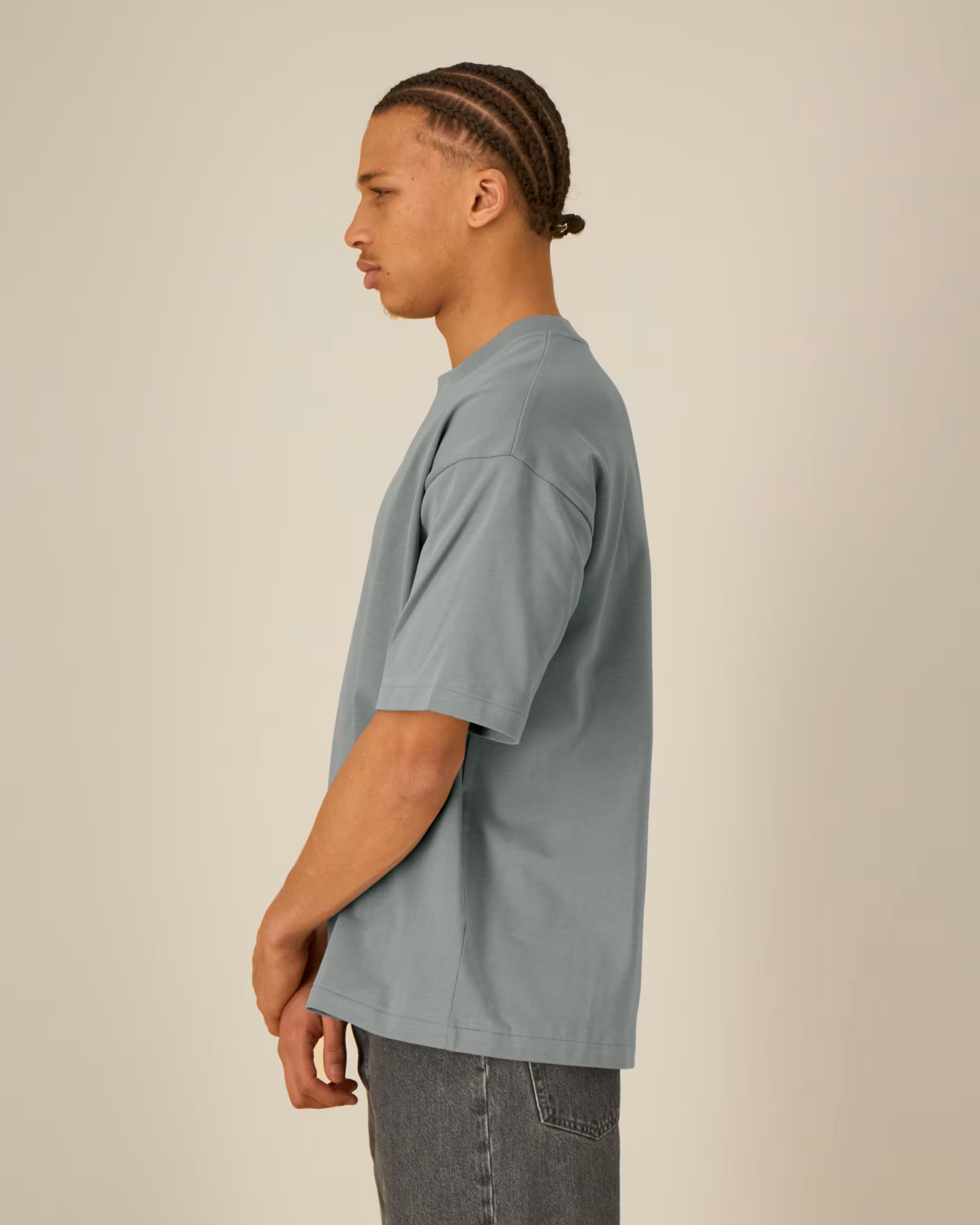 Side view of a model wearing a grey cotton t-shirt in a studio setting