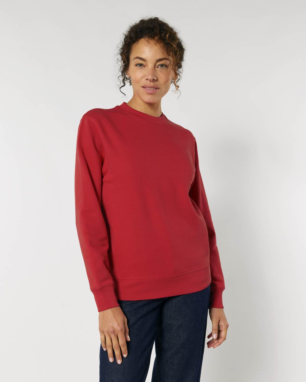 Woman wearing a red unisex cotton sweater against a white background