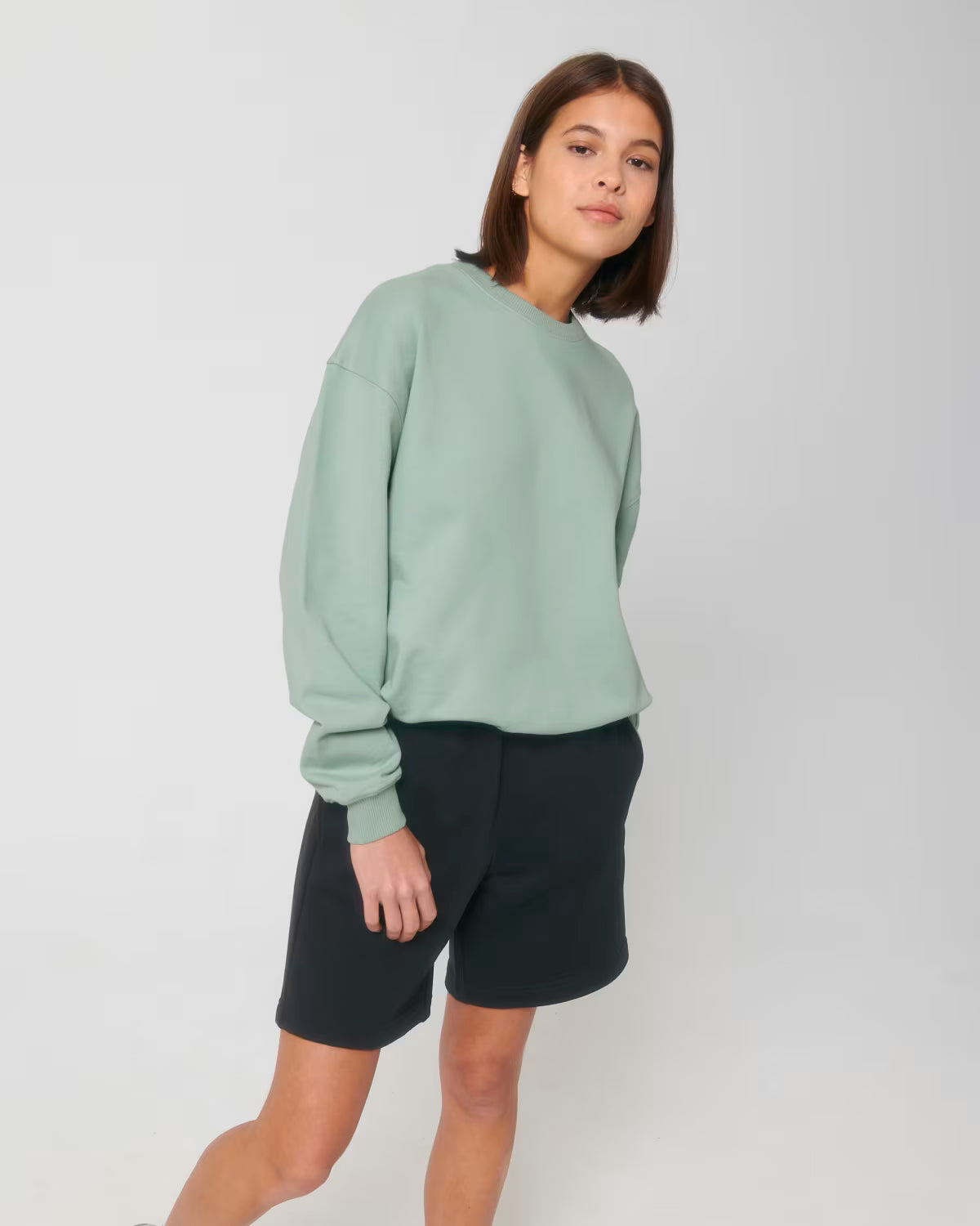 Front view of a female model wearing a mint green cotton hoodie in studio