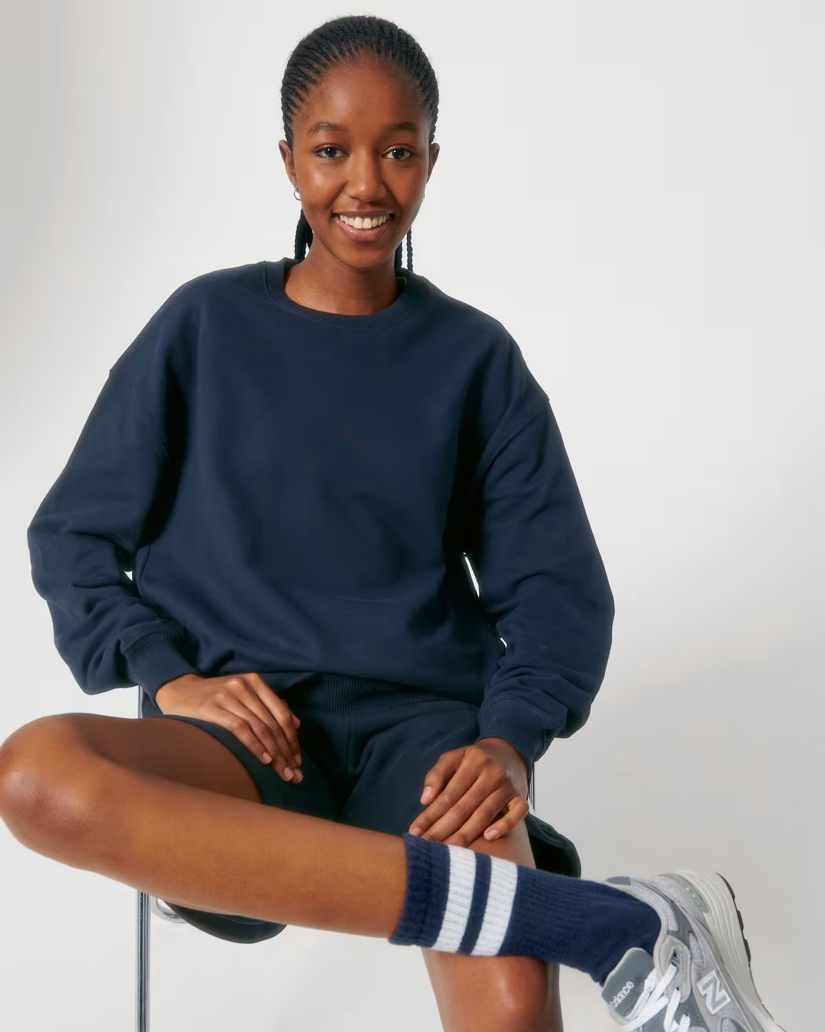 Lifestyle shot of a male model wearing a navy cotton hoodie sitting in studio