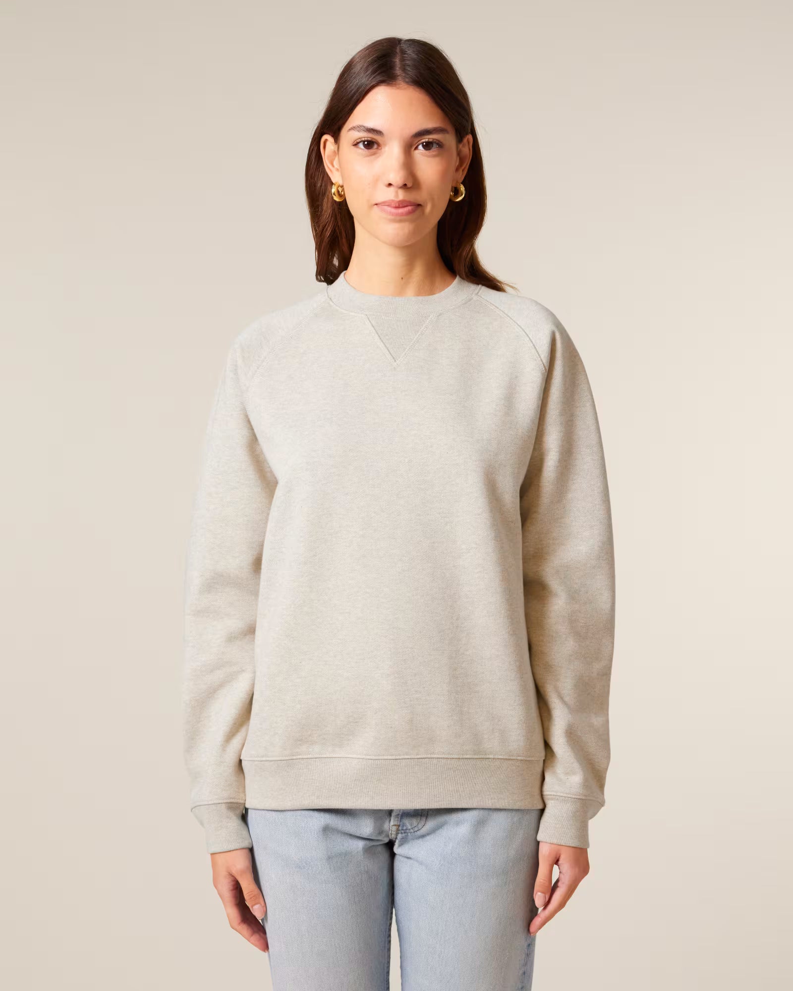 Front view of a female model wearing a beige cotton sweatshirt in studio