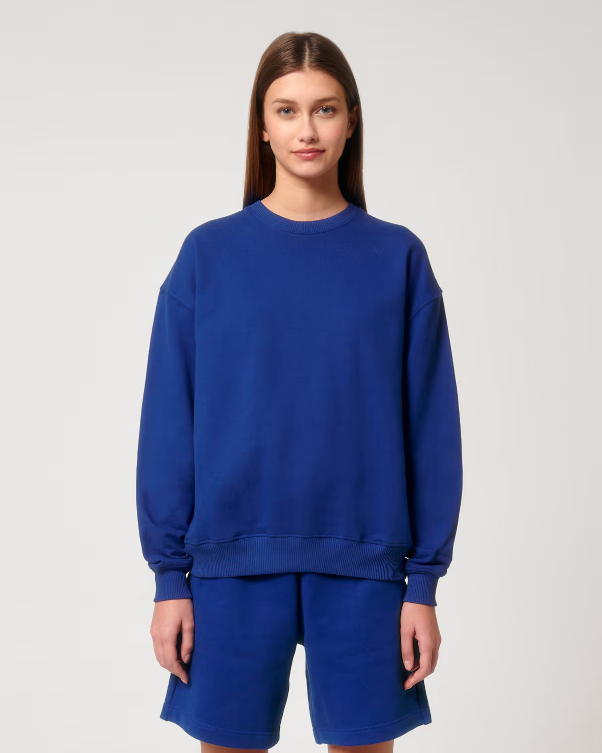 Front view of a female model wearing a royal blue cotton hoodie in studio