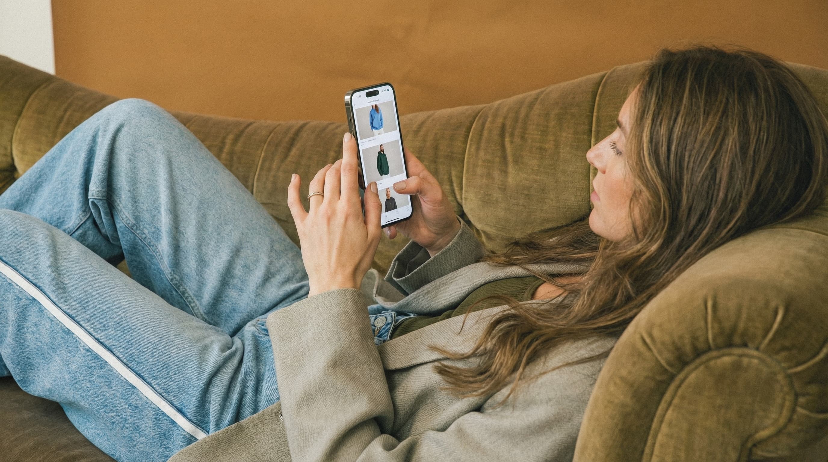 Woman watching catalog on a couch using a smartphone with a blurred background