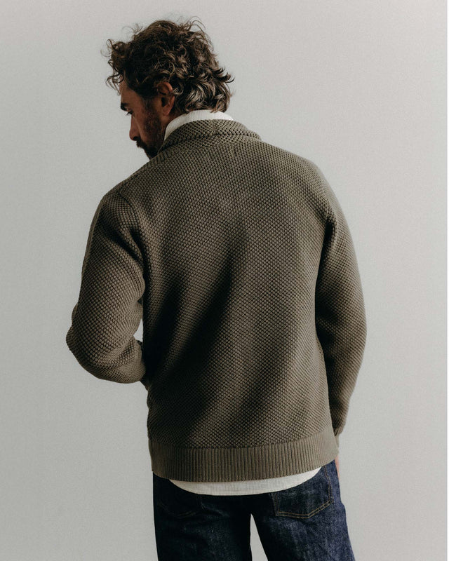 Man wearing a brown knitted sweater against a plain background