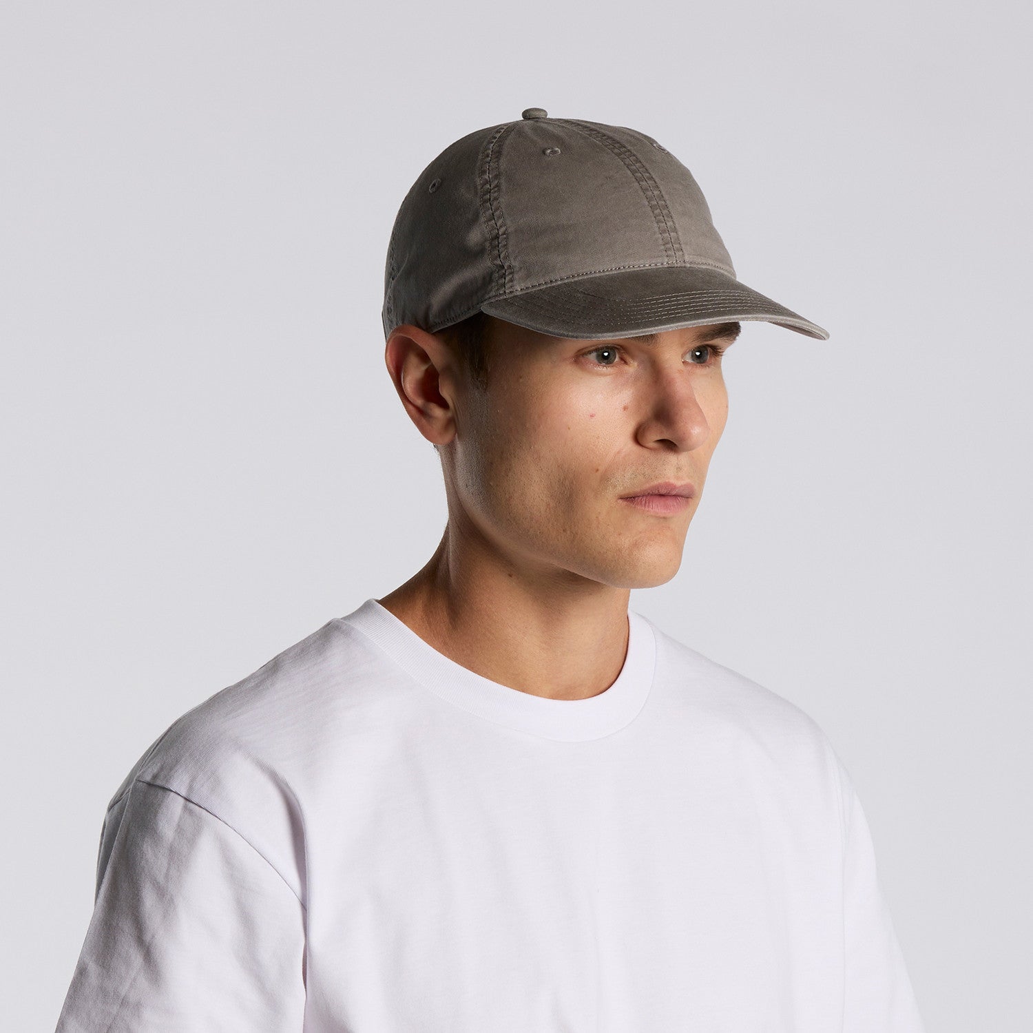Man wearing a gray unisex cotton cap and white shirt against a light gray background