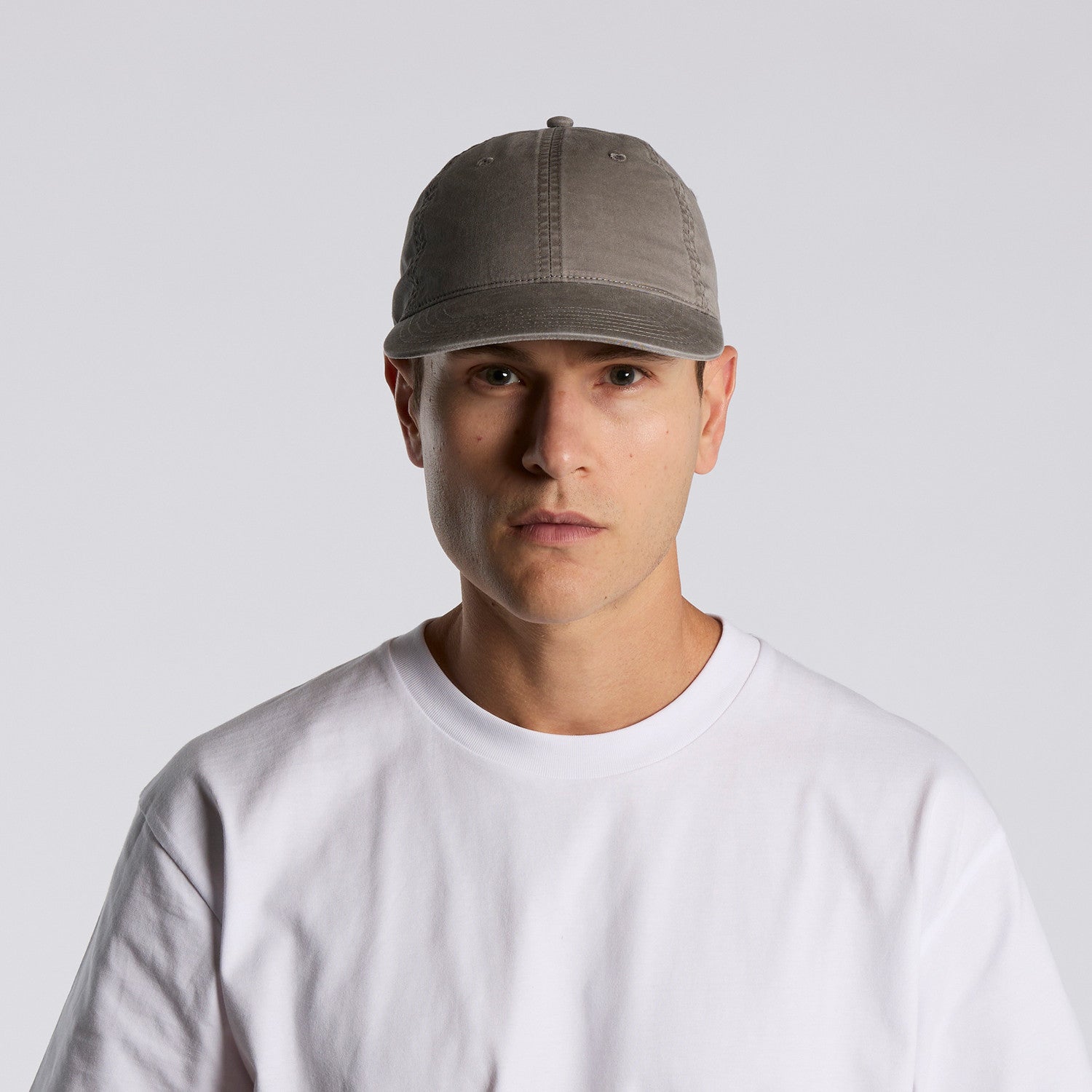 Man wearing a gray unisex cotton cap and white shirt against a light gray background