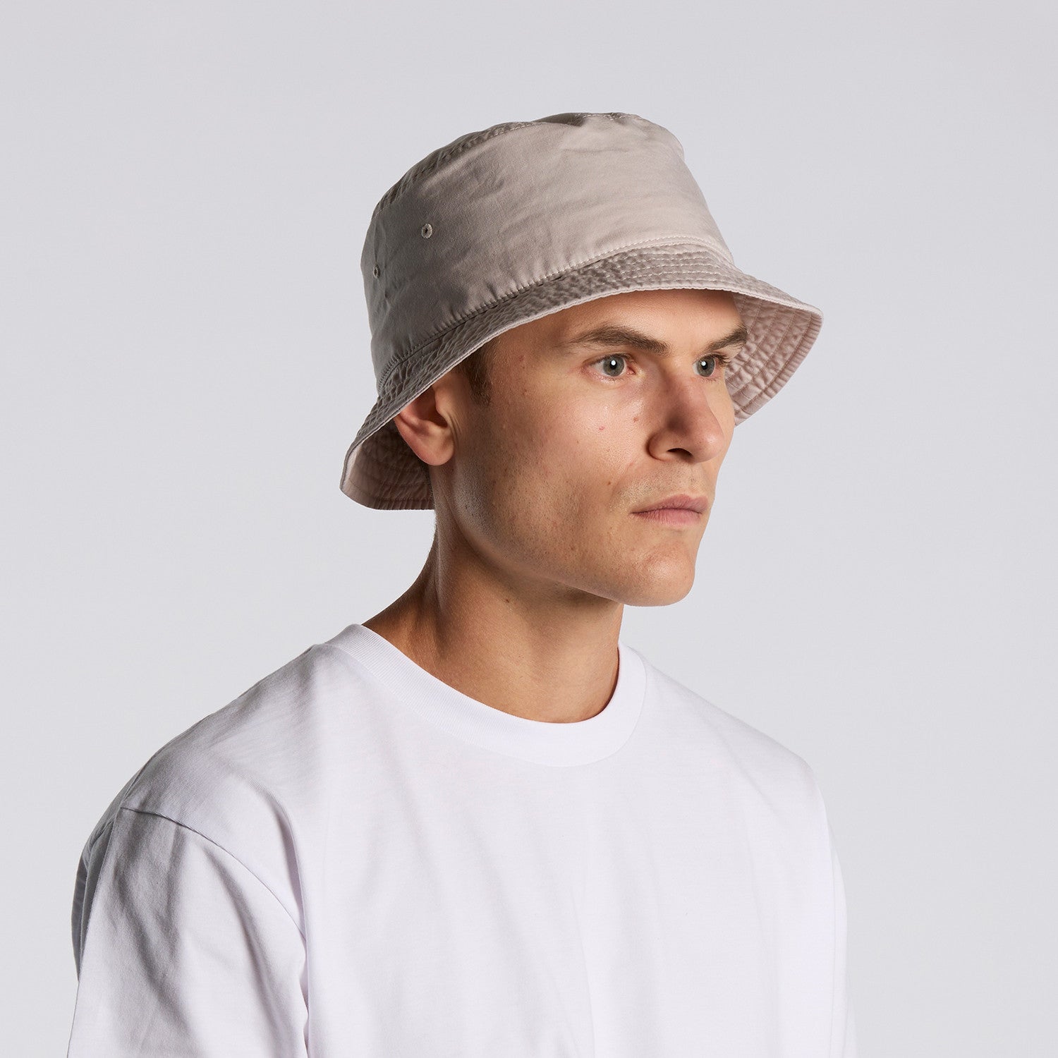 Man wearing a beige bucket hat against a plain background