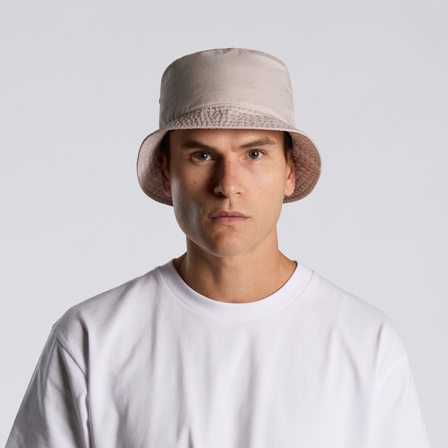 Man wearing a beige bucket hat against a white background