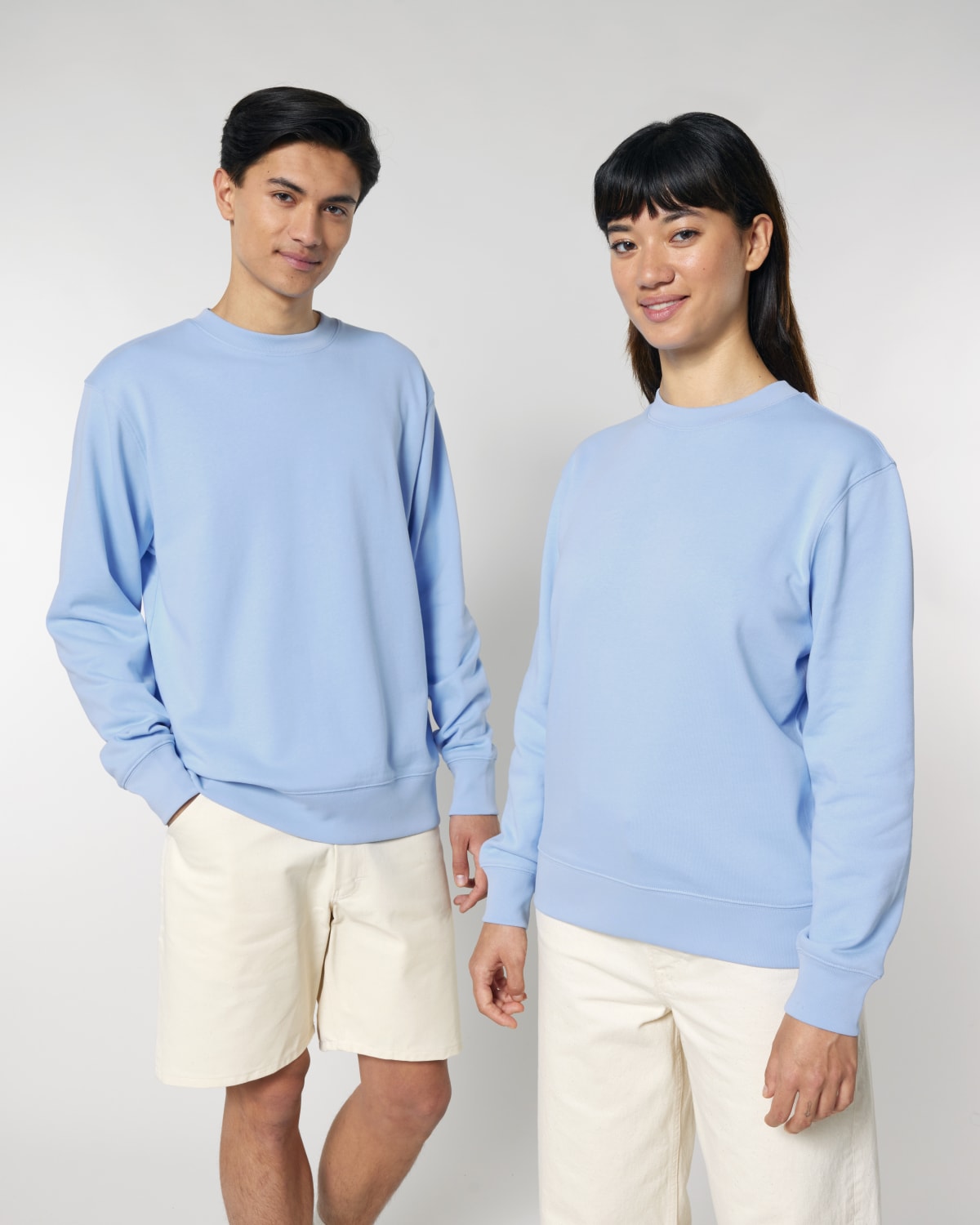 Two people wearing light blue unisex cotton hoodie isolated on white background