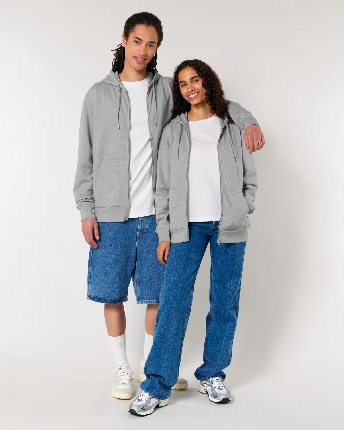 Two people wearing cotton gray hoodies relaxed fit and blue jeans on a white background