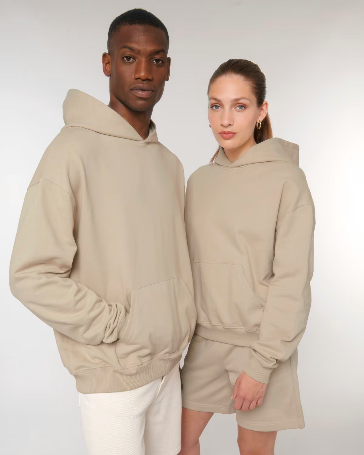 Front view of a male and female model wearing beige cotton hoodies in studio