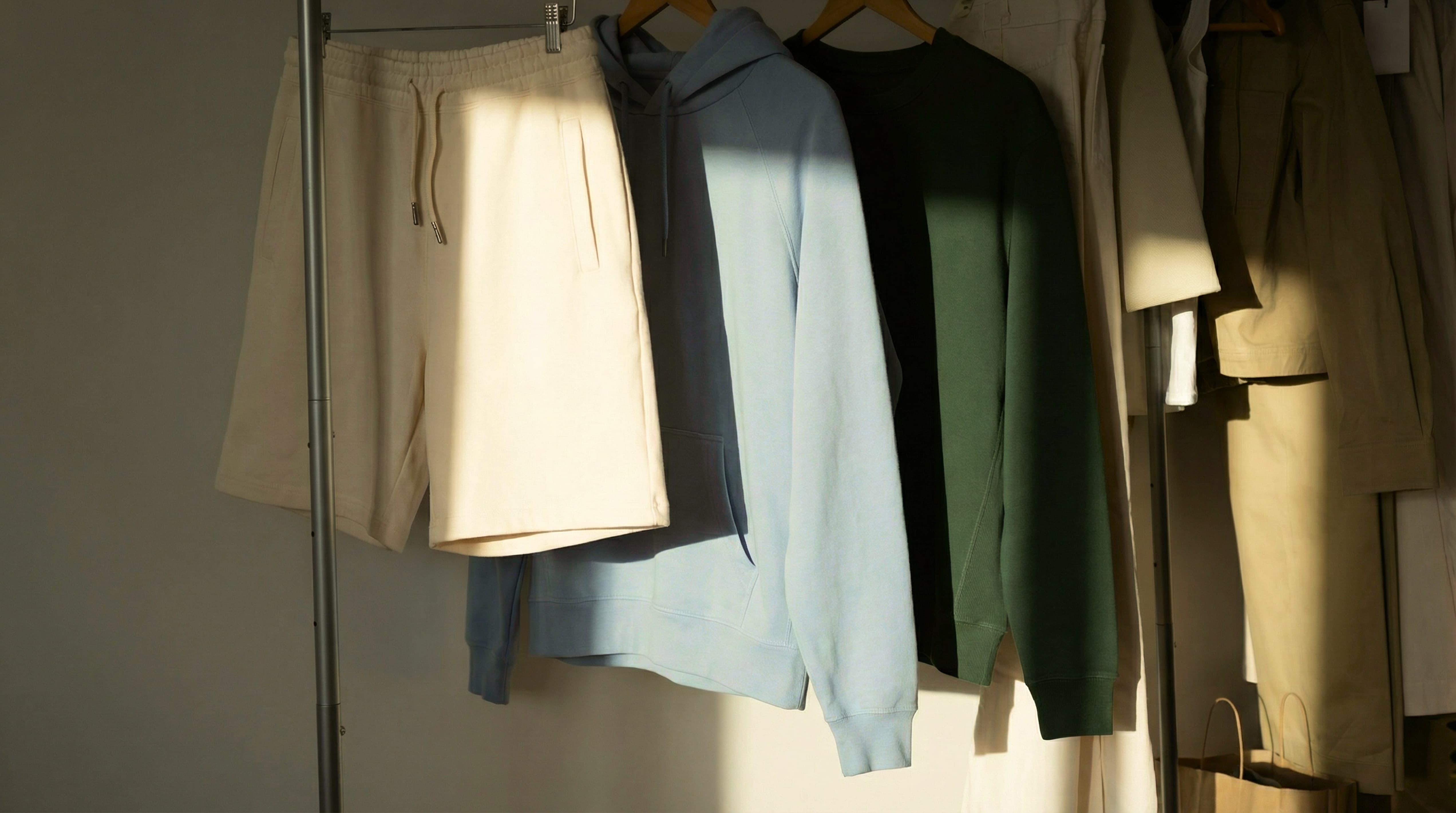 Clothing items hanging on a rack with a neutral background