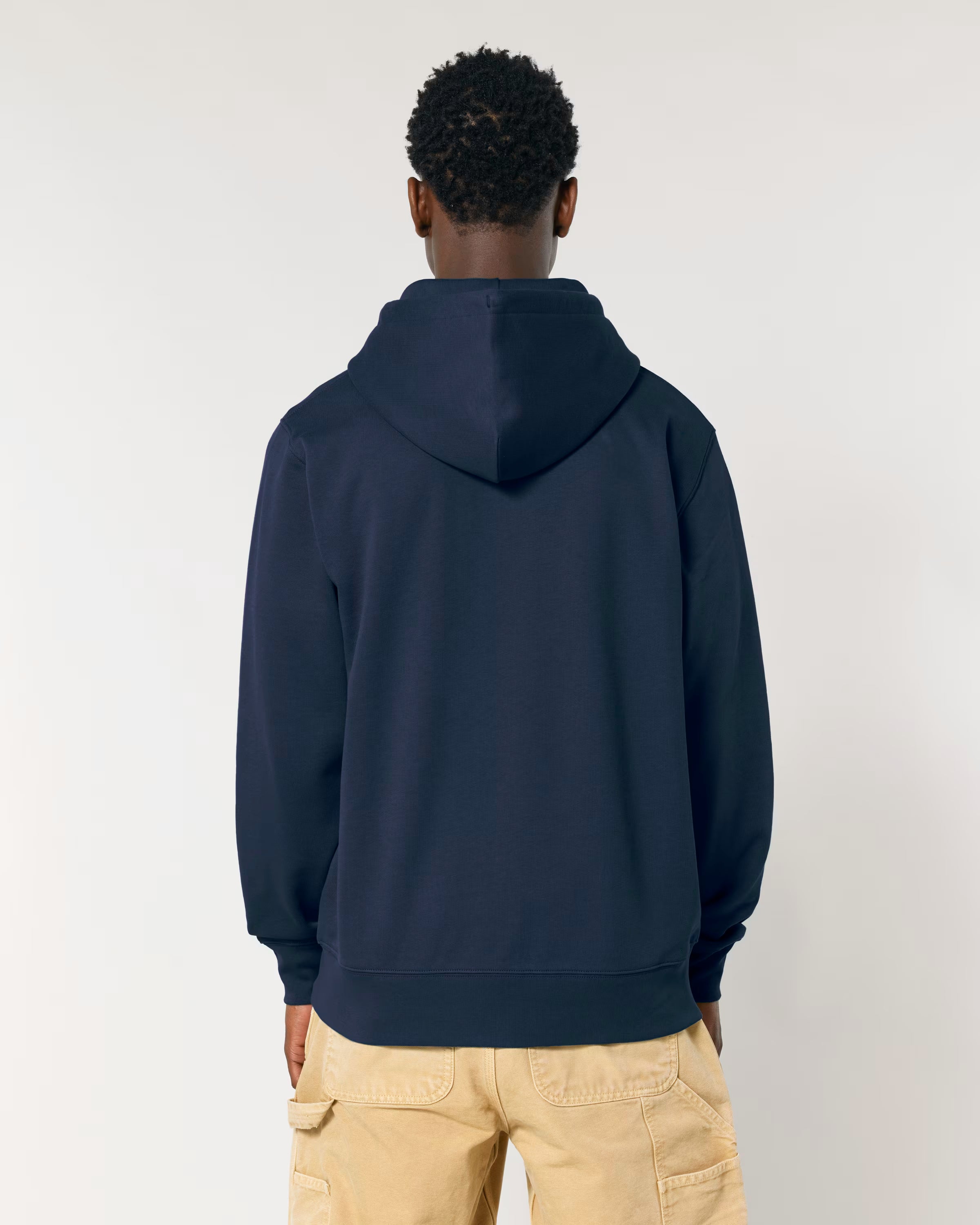 Person wearing a navy blue cotton hoodie and beige pants on a white background