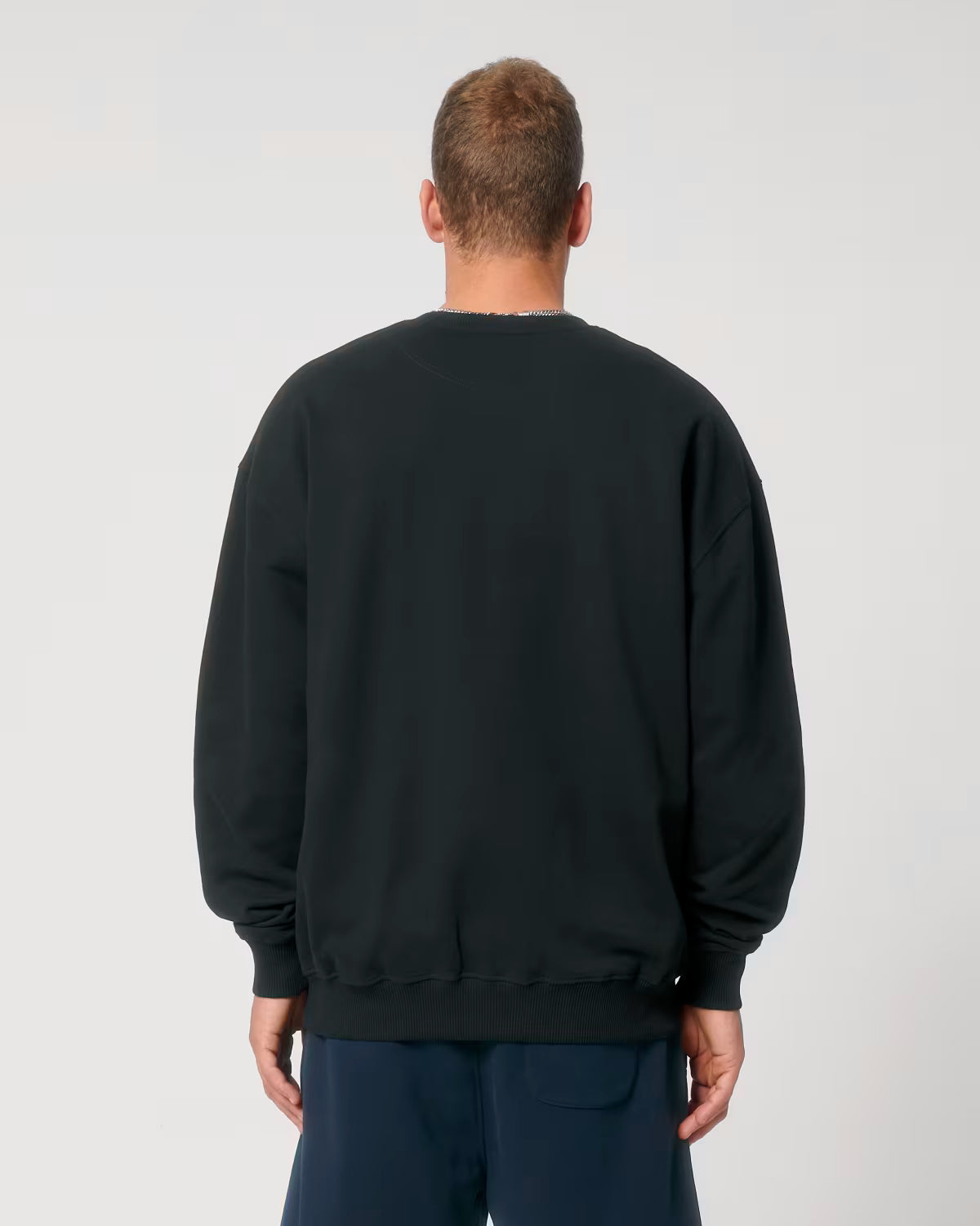 Back view of a male model wearing a black cotton hoodie in studio