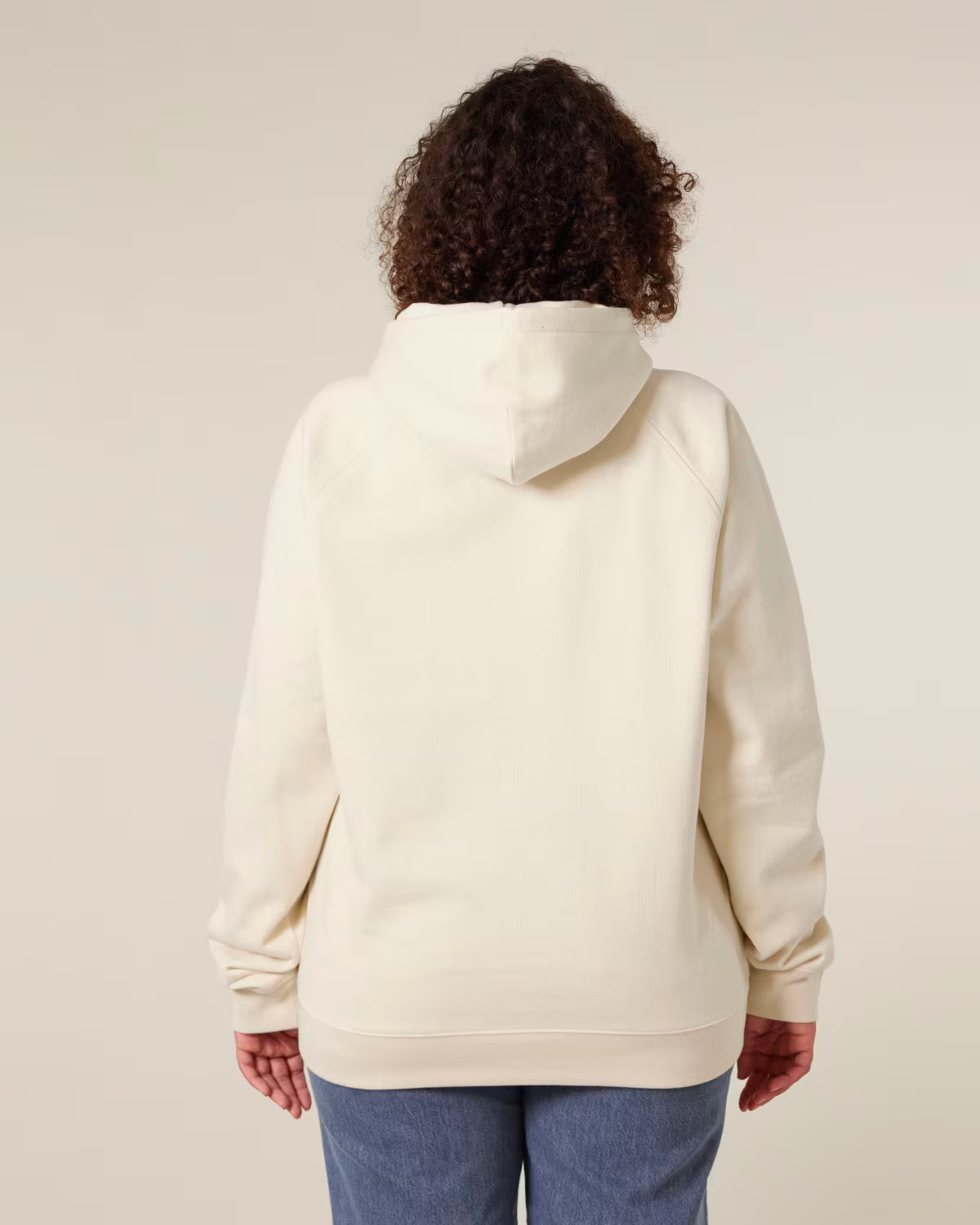 back view of a female model wearing a beige orange cotton hoodie in studio