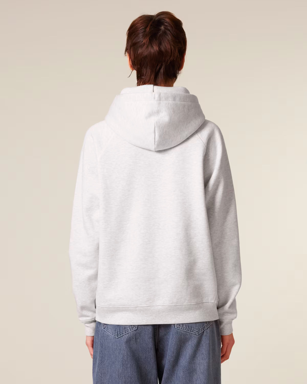 Back view of a female model wearing a white cotton hoodie in studio