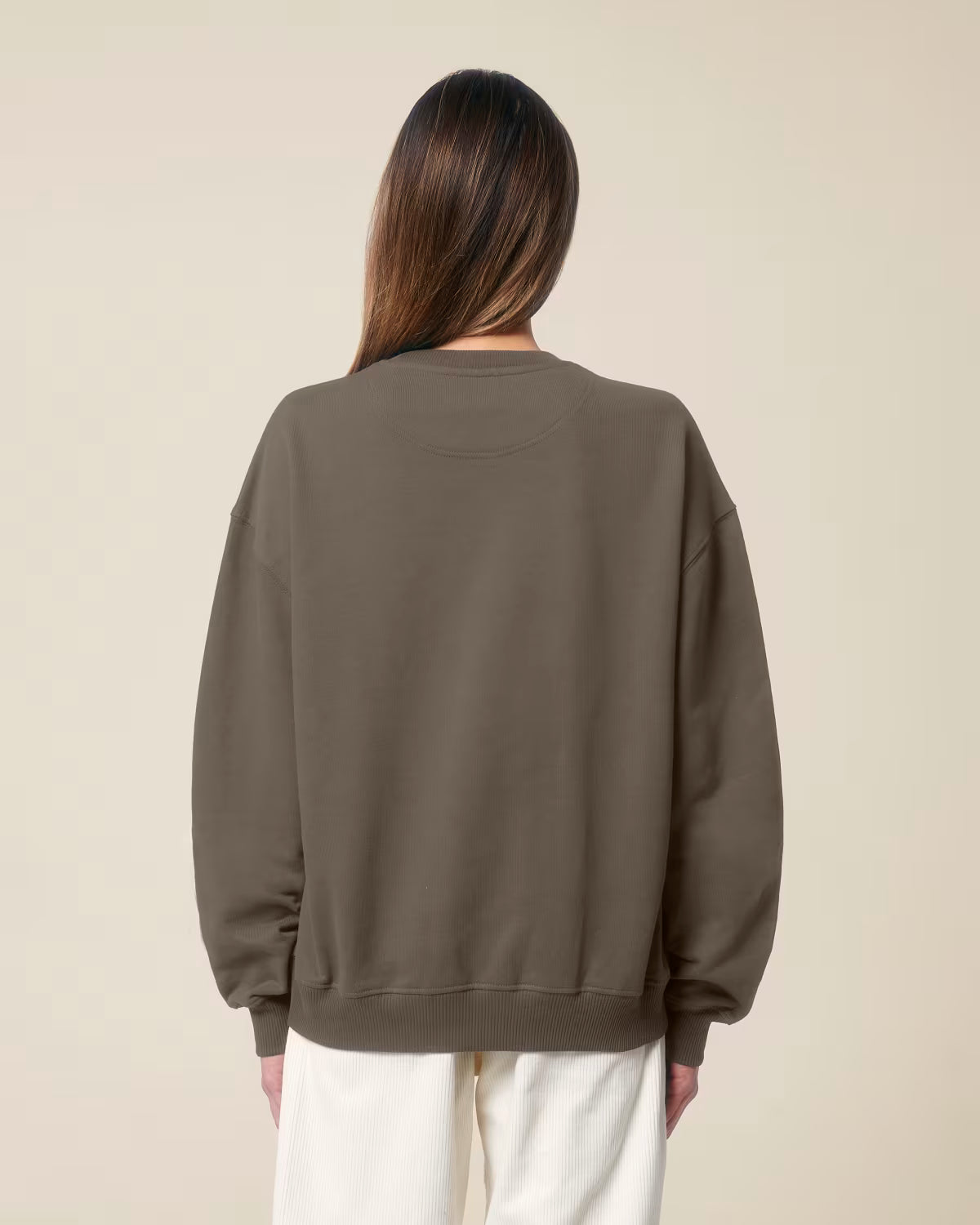 Back view of a female model wearing a brown cotton hoodie in studio