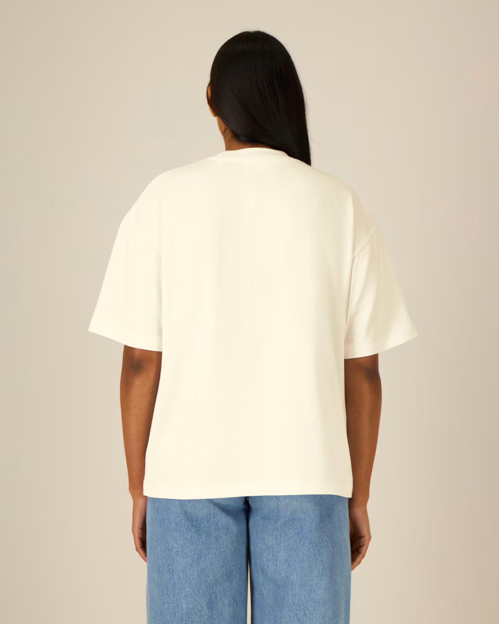 Back view of a female model wearing a natural beige cotton t-shirt in studio