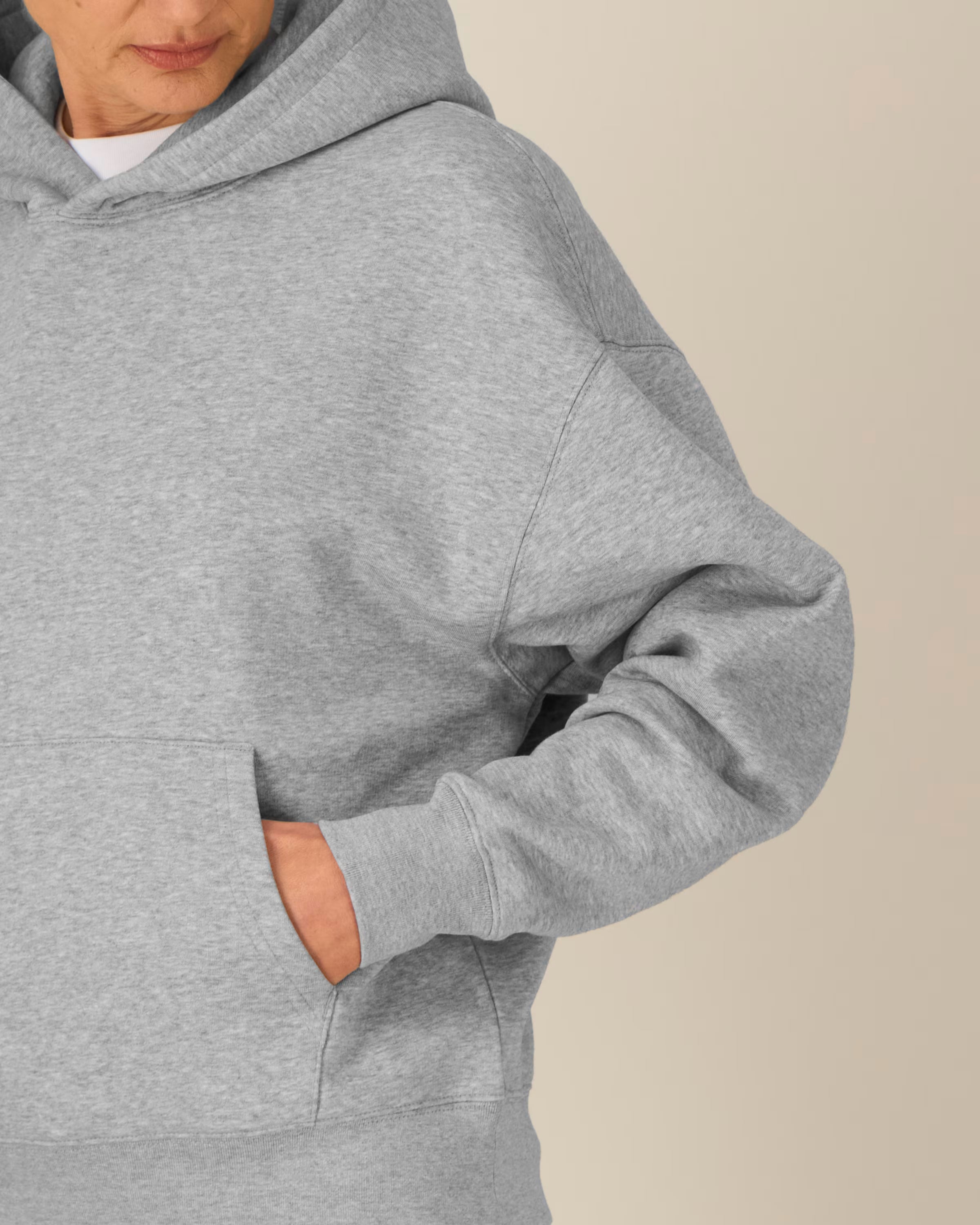 Person wearing a gray unisex cotton hoodie with a neutral background