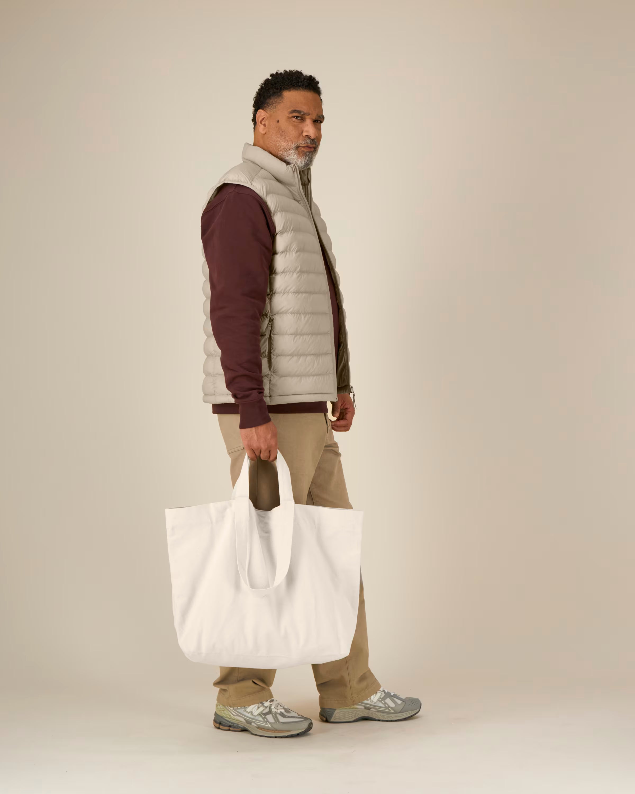 Man unisex cotton holding a white tote bag against a plain background