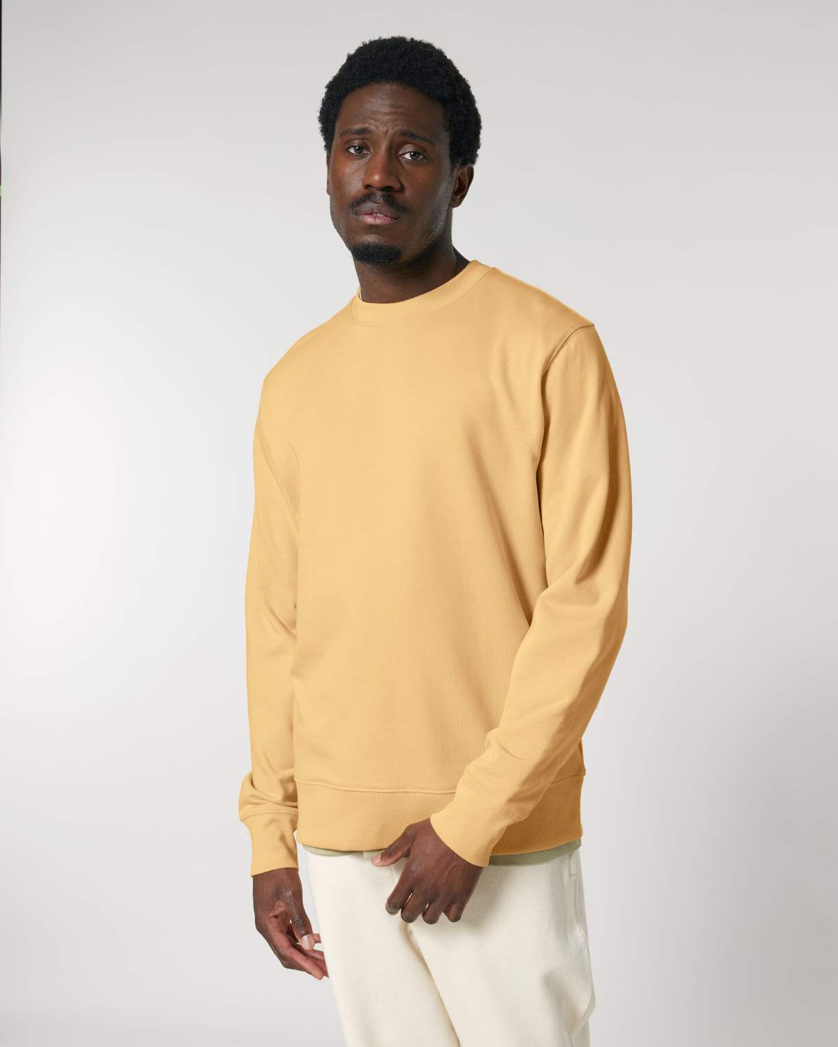 Man wearing a mustard yellow unisex cotton sweater against a plain background