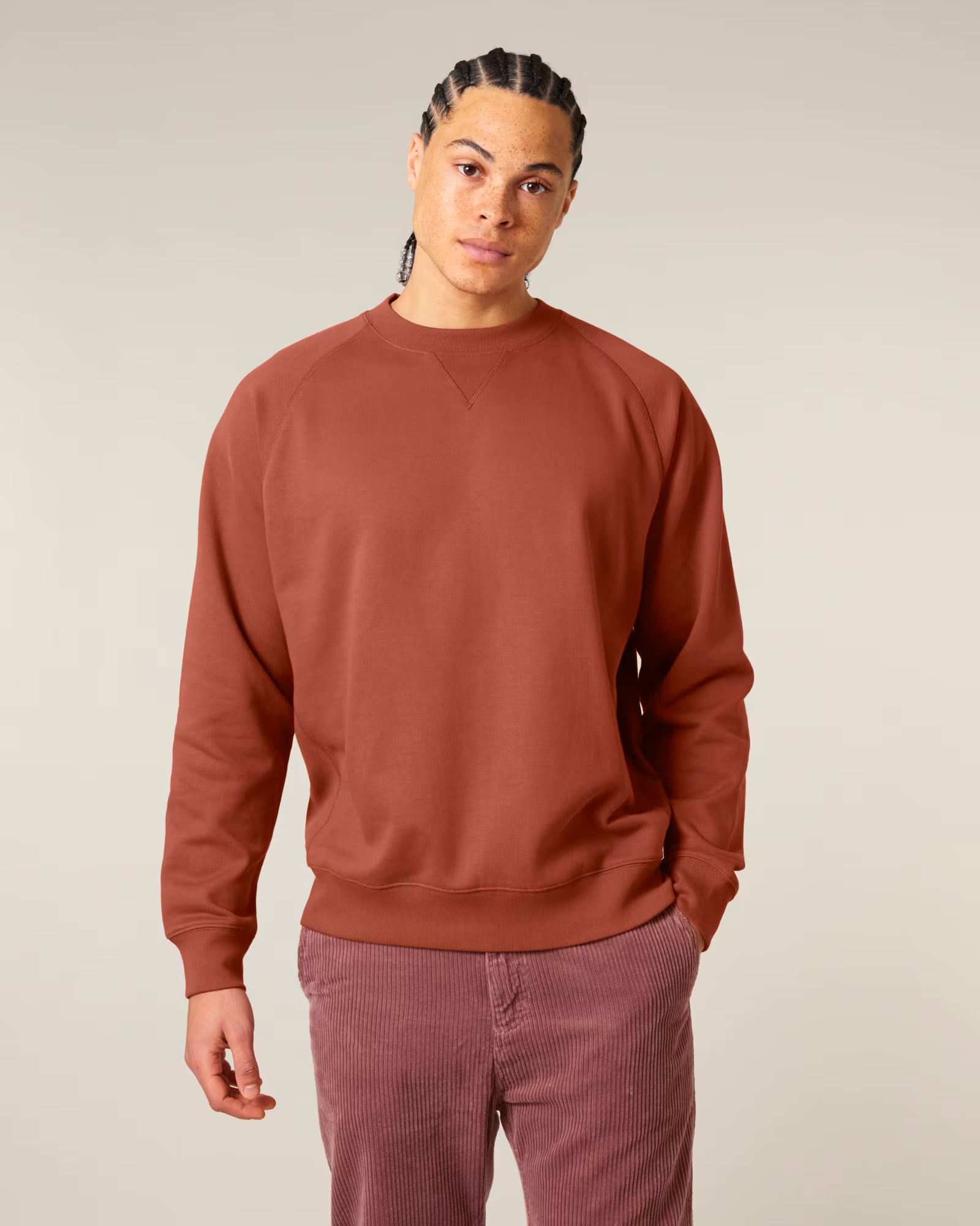 Front view of a male model wearing a rust orange cotton sweatshirt in studio