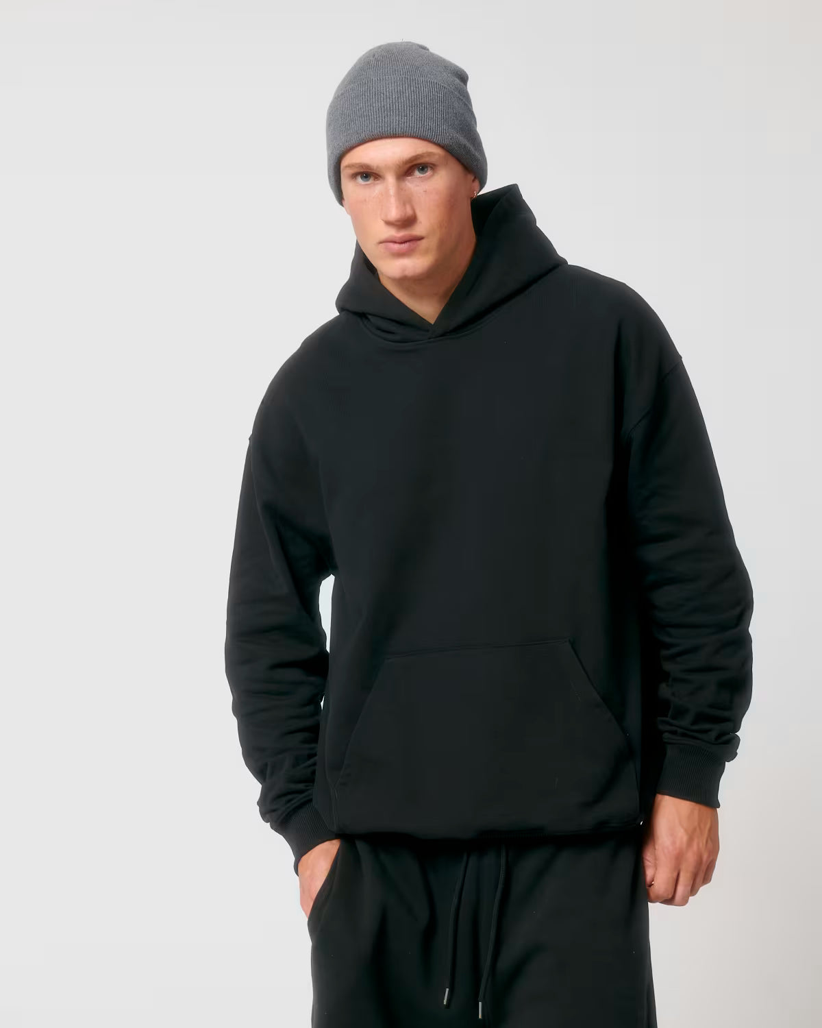 Front view of a male model wearing a black cotton hoodie in studio