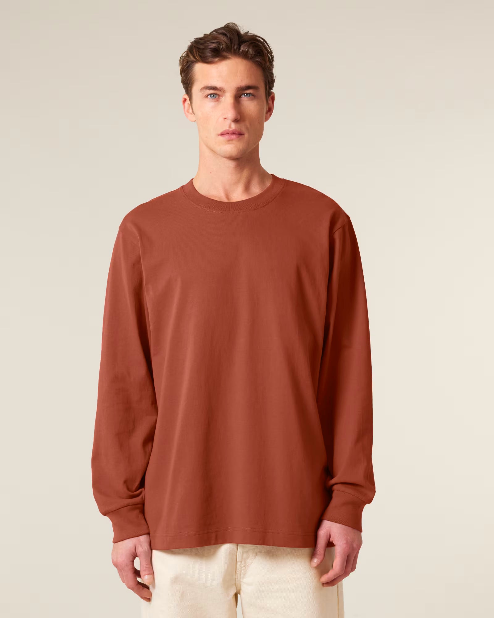 Front view of a male model wearing a rust orange cotton long sleeve t-shirt in studio