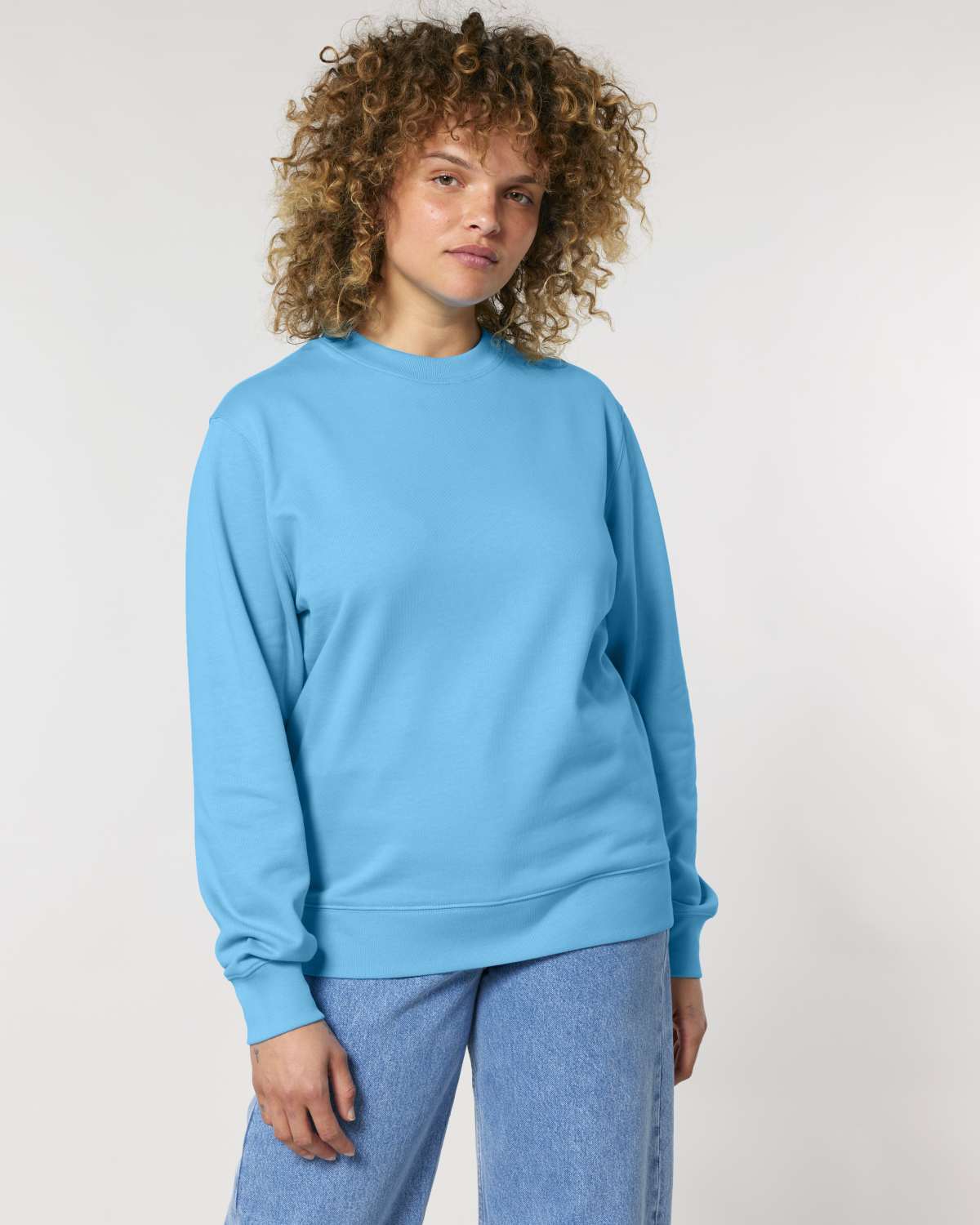 Person wearing a light blue unisex cotton sweatshirt against a plain background