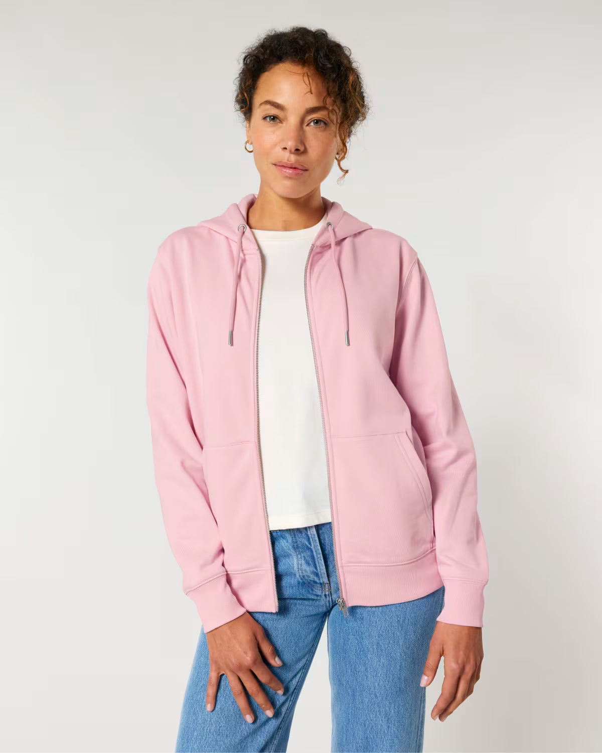 Person wearing a cotton pink hoodie, white shirt, and blue jeans on a plain background