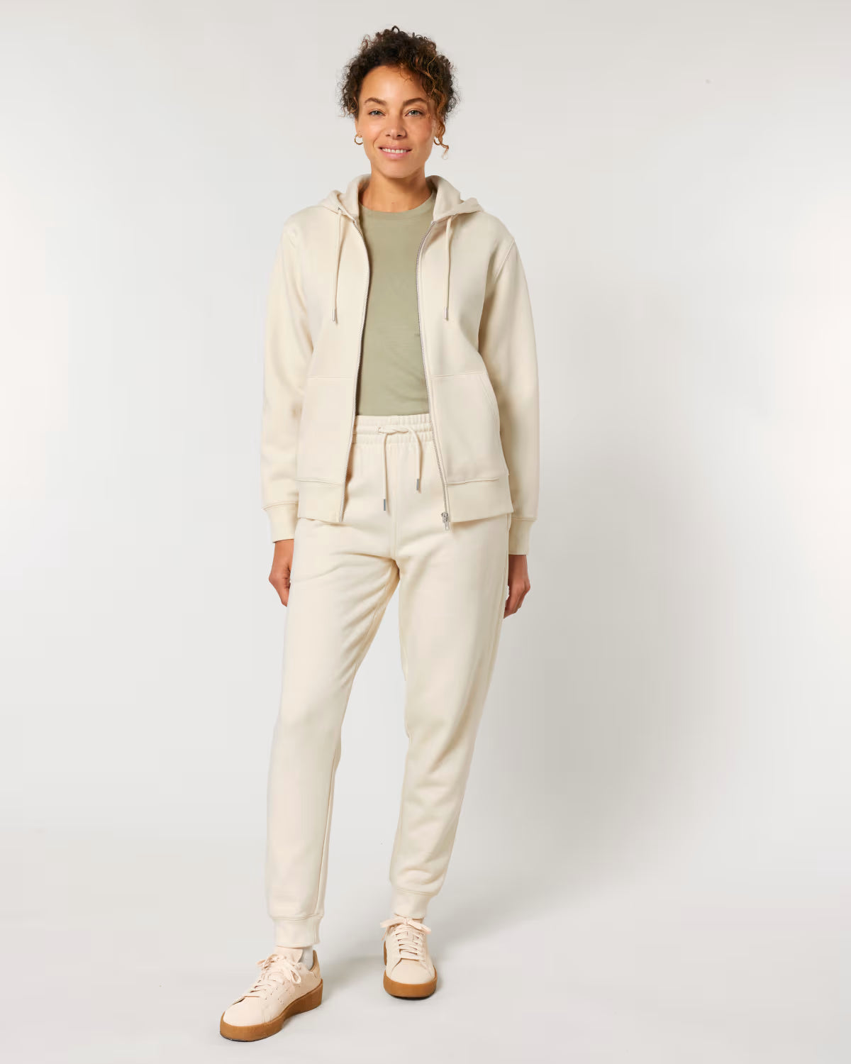 Person wearing a cotton beige tracksuit on a white background