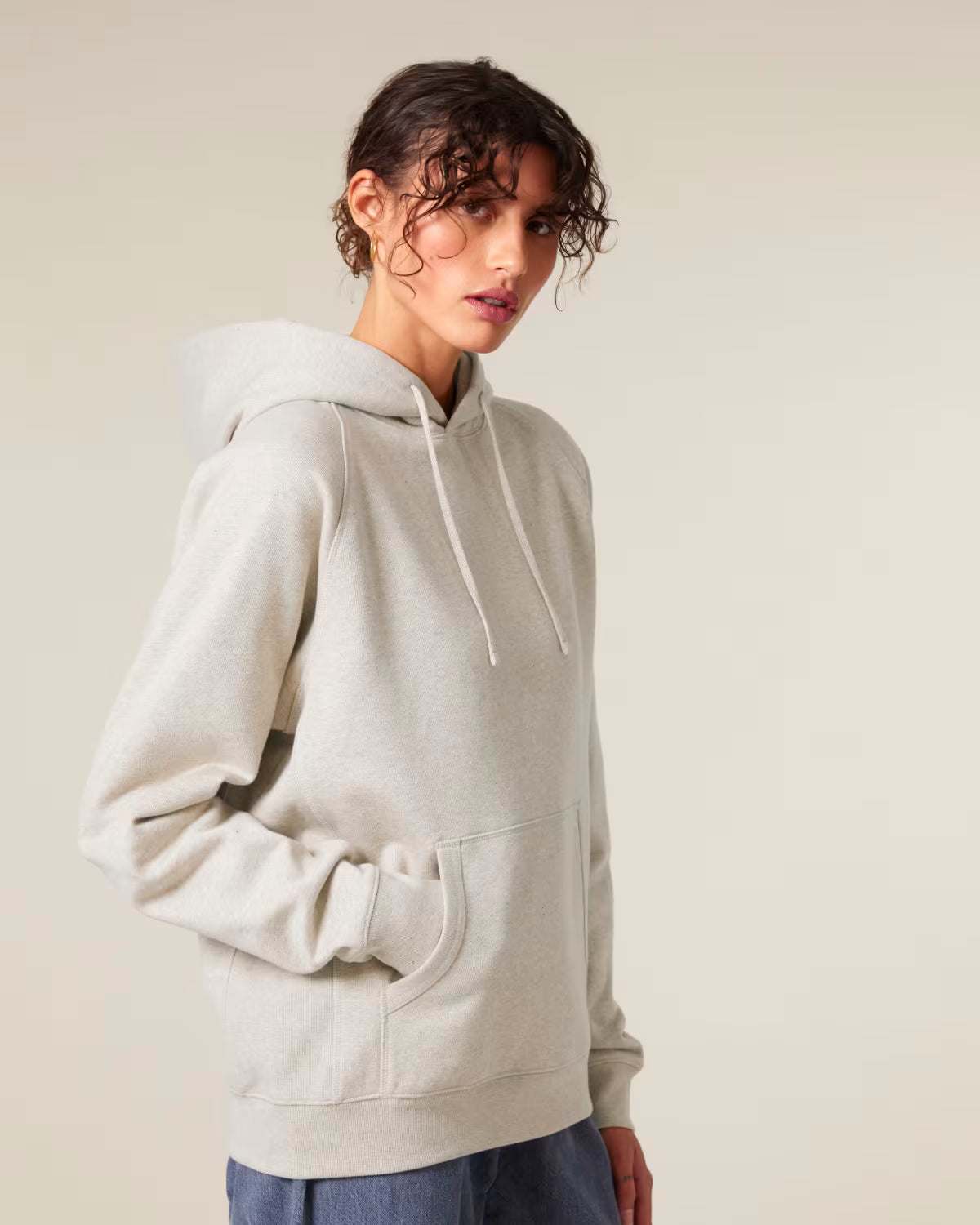Side view of a male model wearing a beige cotton hoodie in studio